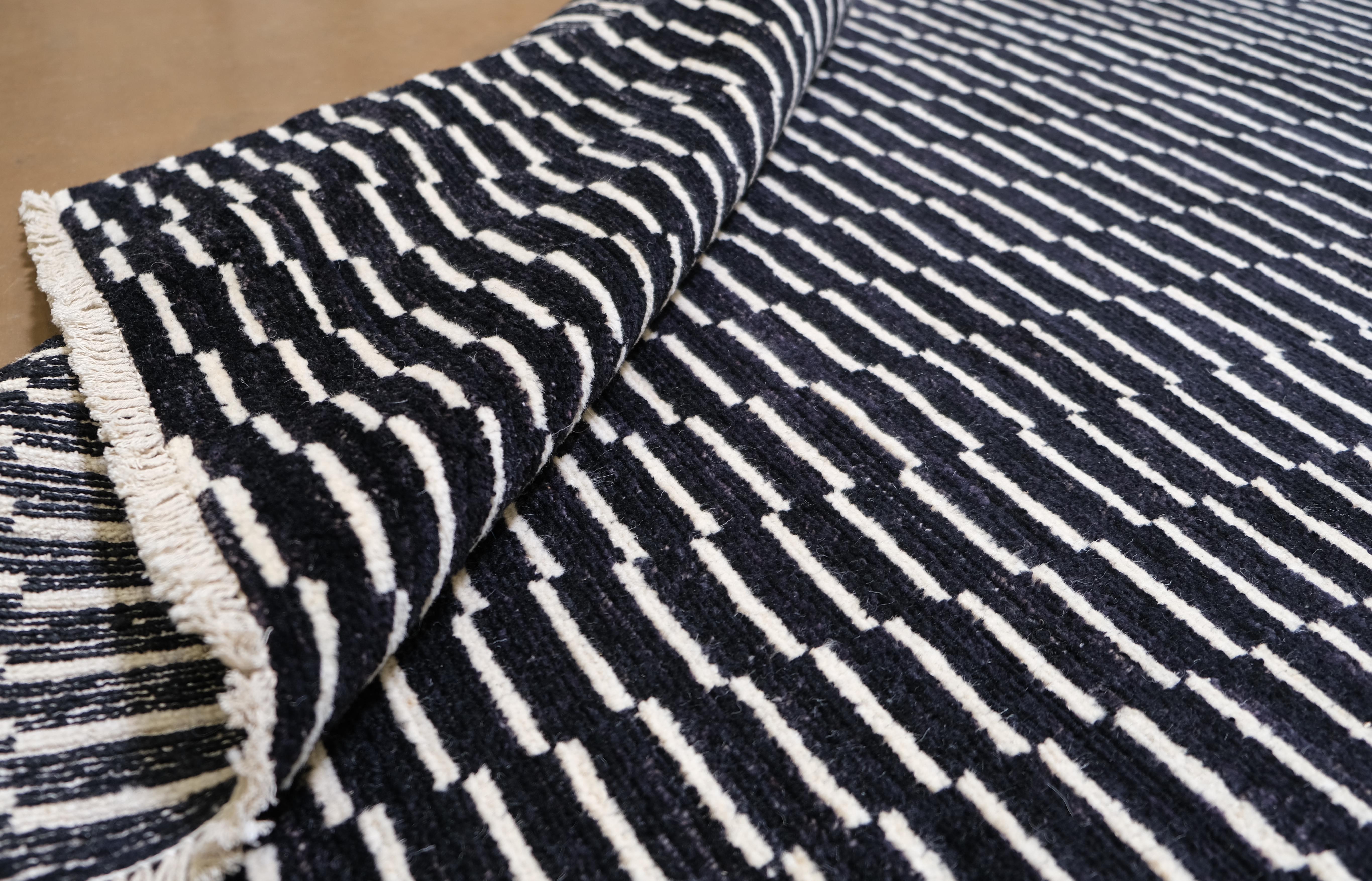 Trasforma il tuo spazio con l'eleganza dinamica di questo tappeto in lana annodato a mano. Caratterizzato da un disegno geometrico in bianco e nero, questo tappeto crea un effetto sorprendente, aggiungendo profondità e carattere a qualsiasi