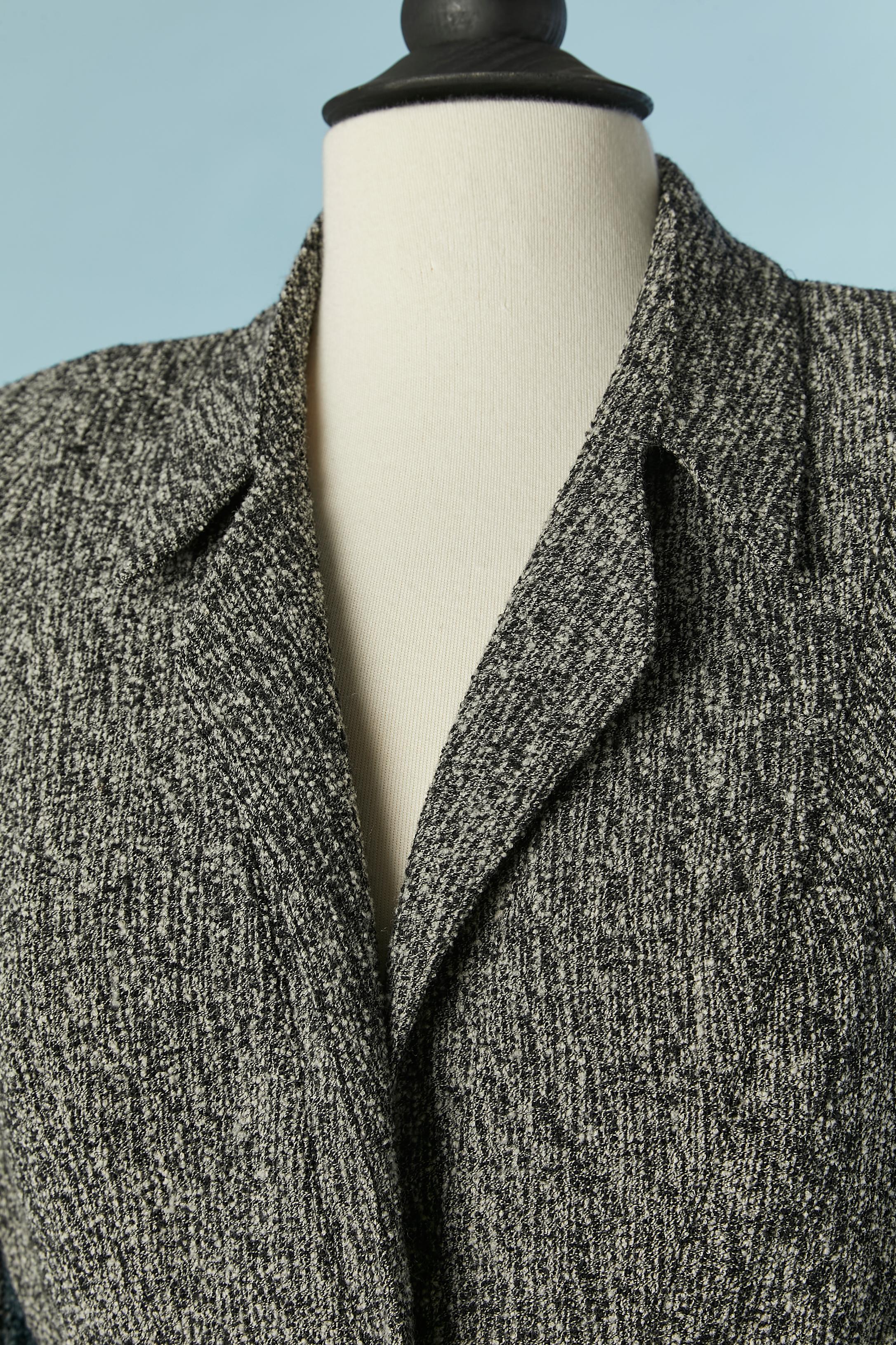 Combinaison en tweed noir et ivoire. Composition du tissu principal : 87% laine, 13% polyamide. Doublure en acétate ou en rayonne (pas d'étiquette indiquant la composition du tissu pour la doublure) 
Fermeture à bouton-pression au milieu du devant.