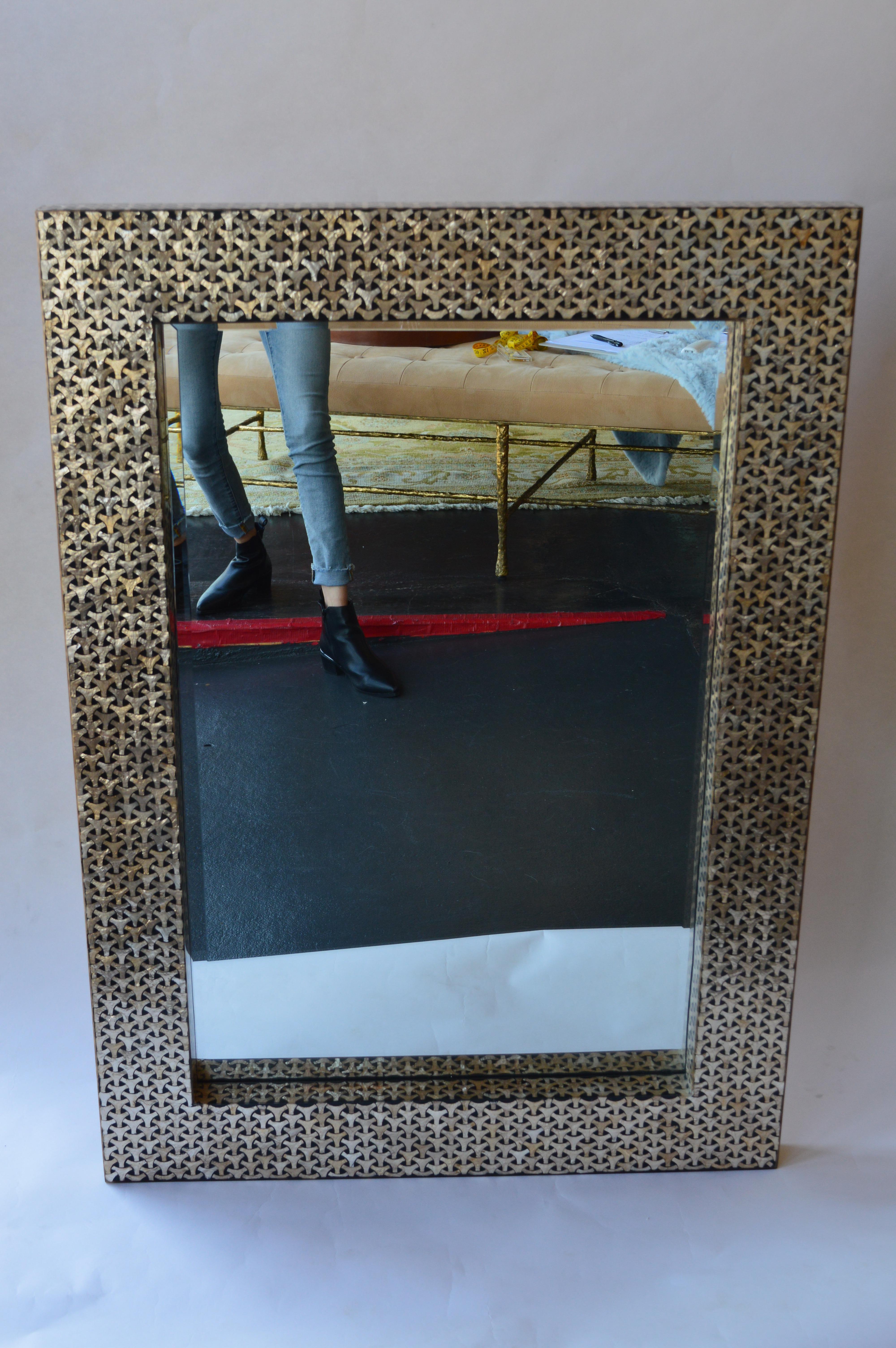 Mirror with geometric mother of pearl design set in a black frame. The mirror can be hung both vertically and horizontally.