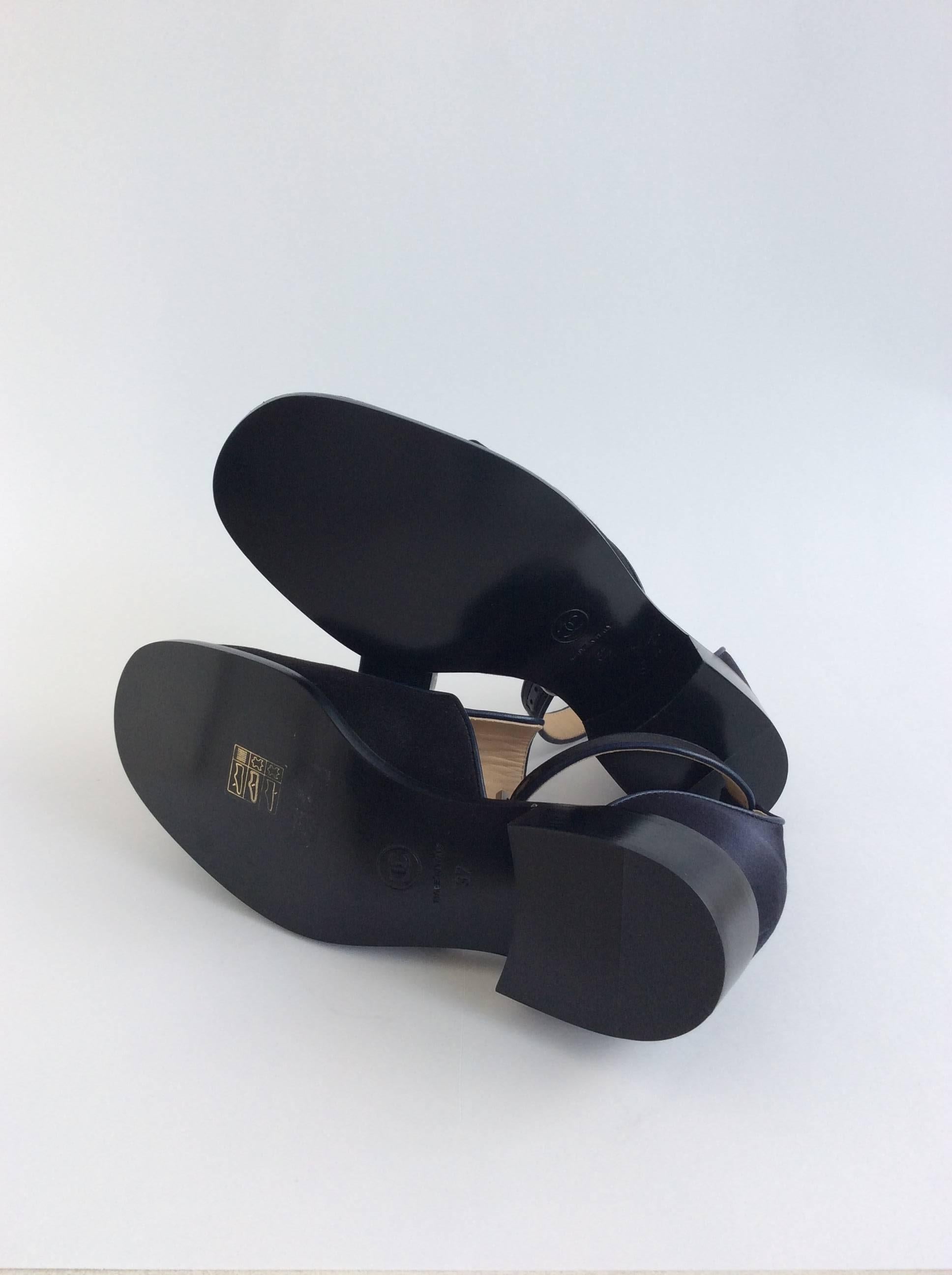 Black and navy satin Chanel Sandals with black grosgrain bows and ankle strap. 

Sizing: Fr37, Us7
Heel height: 1.25 inches