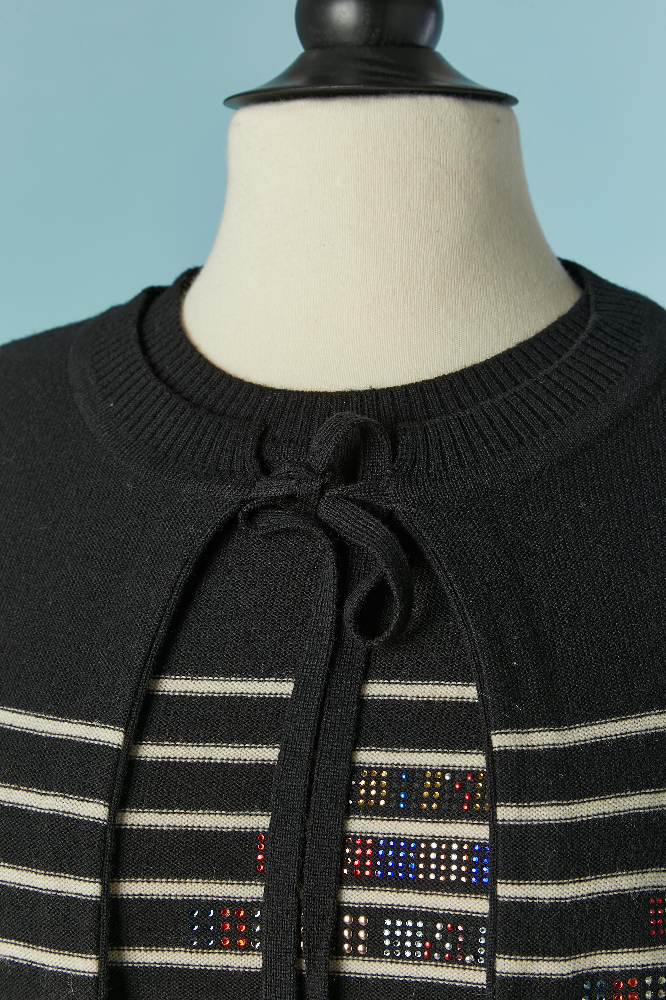 Set di gemelli in maglia nera e bianca con motivo a righe e strass. Una mezza cintura a maglia con fibbia su entrambi i lati del cardigan e una cintura a maglia con coulisse sul bordo inferiore del top. 
Composizione della maglia: 90% lana, 10%