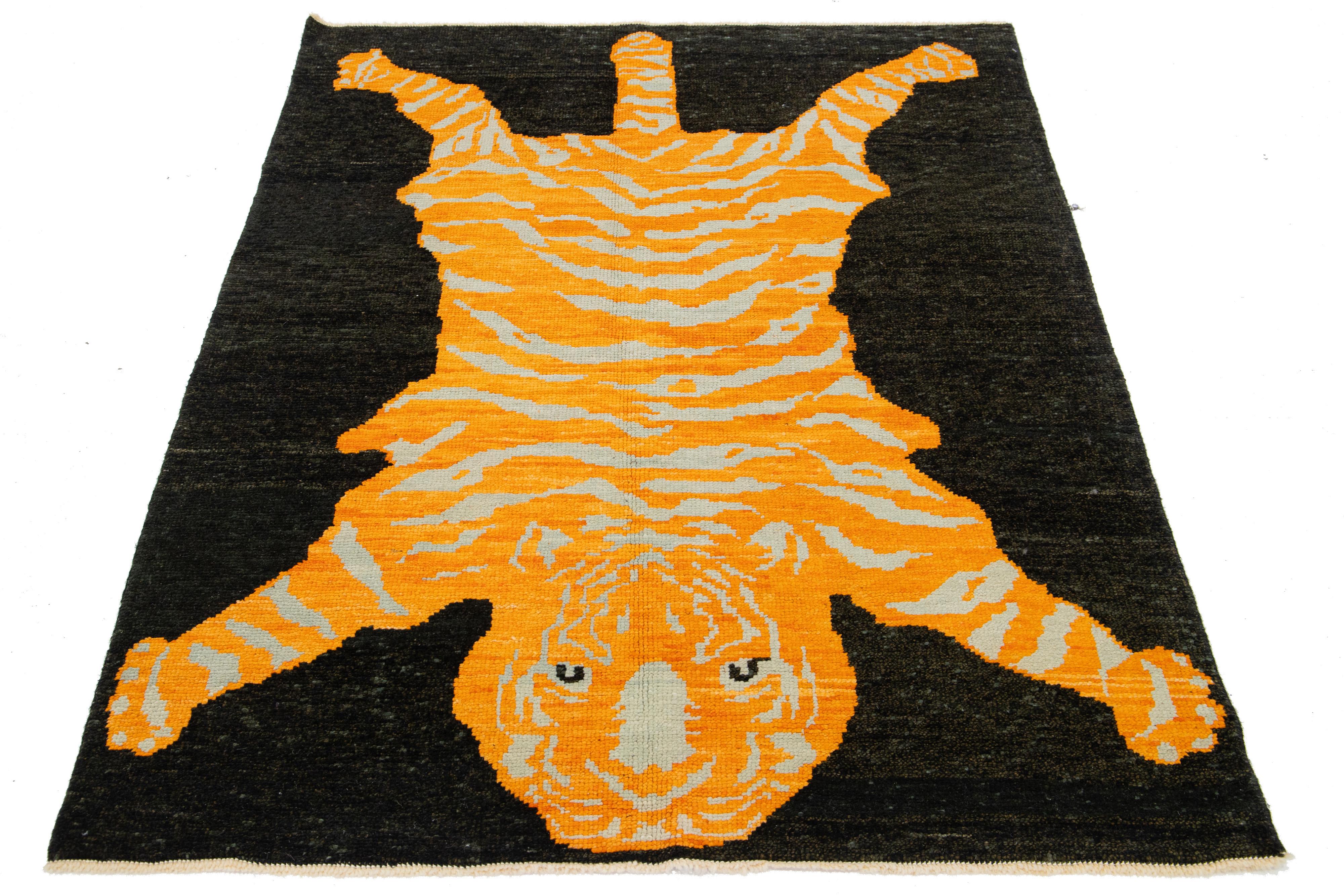 This is a beautiful handmade Turkish Art Deco wool rug with a black field and orange and beige accent colors in a gorgeous tiger pictorial design. 

This rug measures 4'10