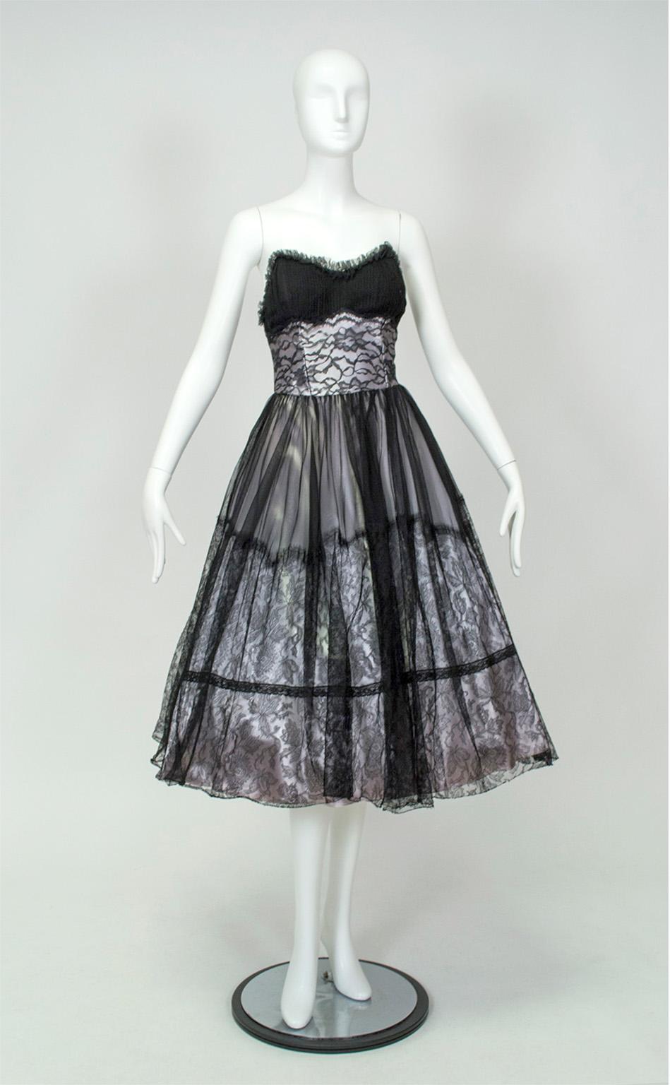 Este vestido de fiesta, inusual y discretamente colorido a pesar de su tonalidad oscura, lleva una enagua de satén ombré plateado, que se suaviza a un lavanda pálido cerca del dobladillo. Y lo que es aún mejor, la enagua lleva un encaje de lazo