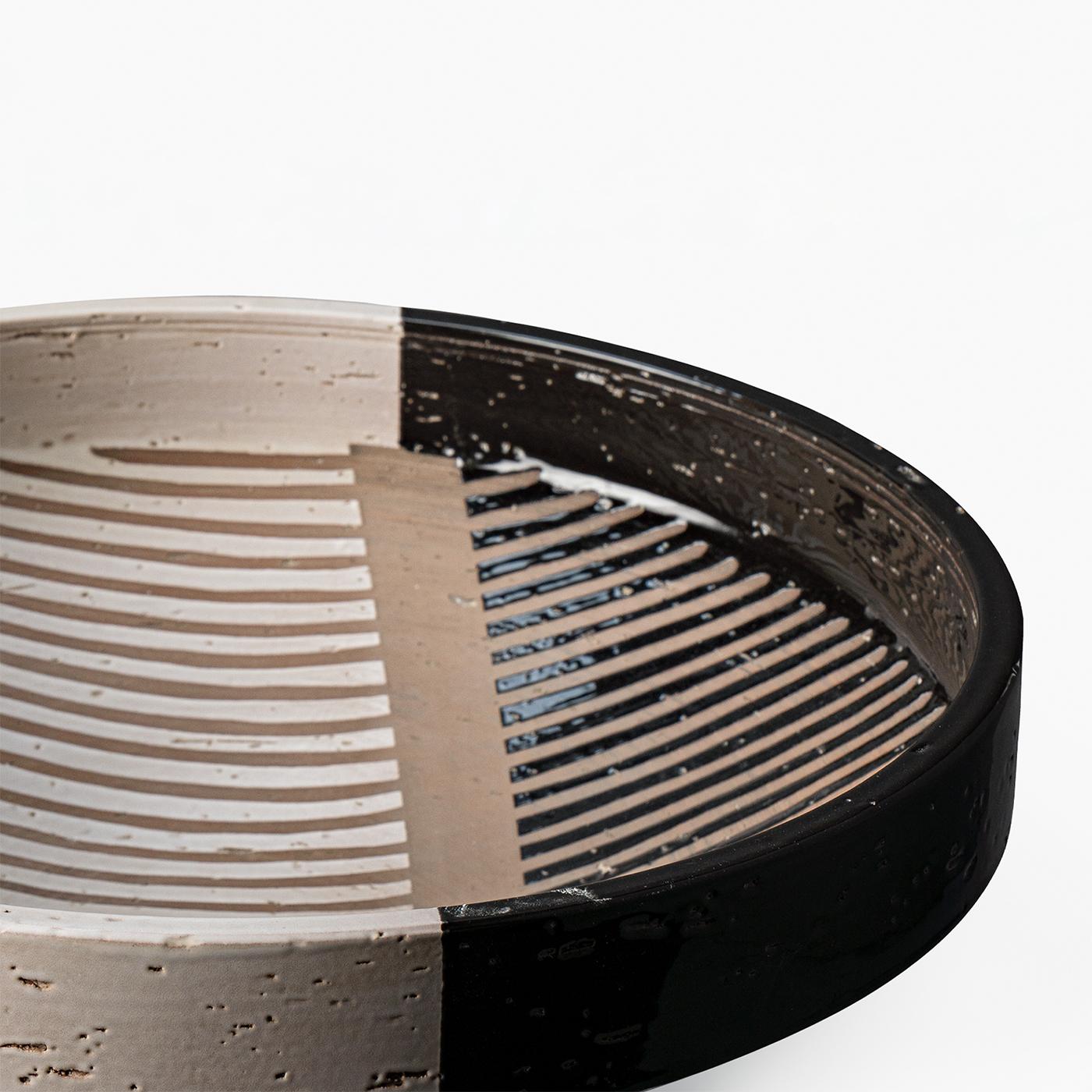 Bolo centerpiece featuring a turned form crafted from refractory red clay. The design showcases an alternating pattern of black and white semi-gloss enamel stripes achieved through a wax resist technique. This medium-sized piece is a limited edition