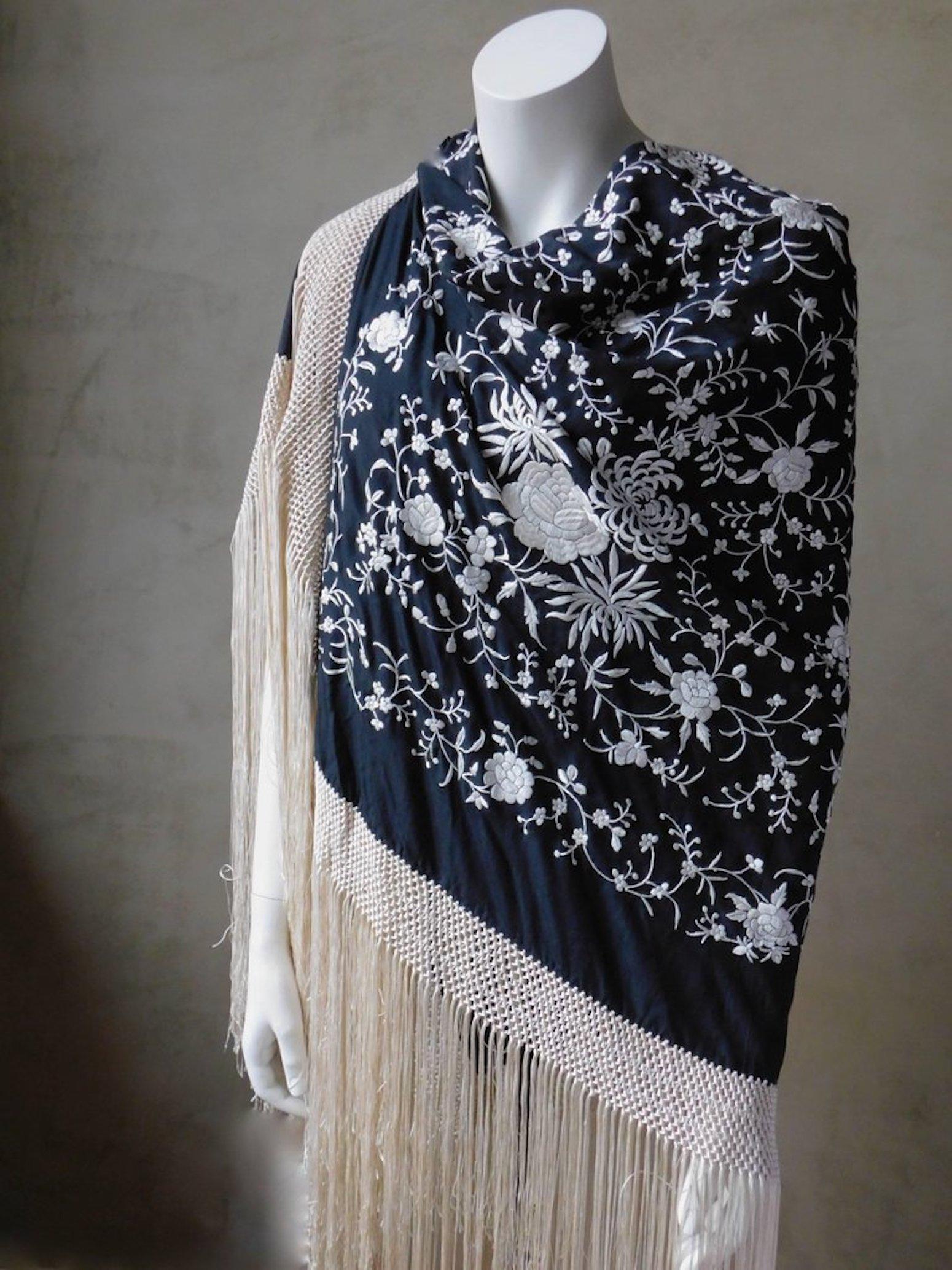 Stunningly elegant black and white Cantonese embroidered silk piano shawl. Black silk heavily hand embroidered with white silk thread and completely finished all around with long macrame tied white very long silk fringe. In excellent