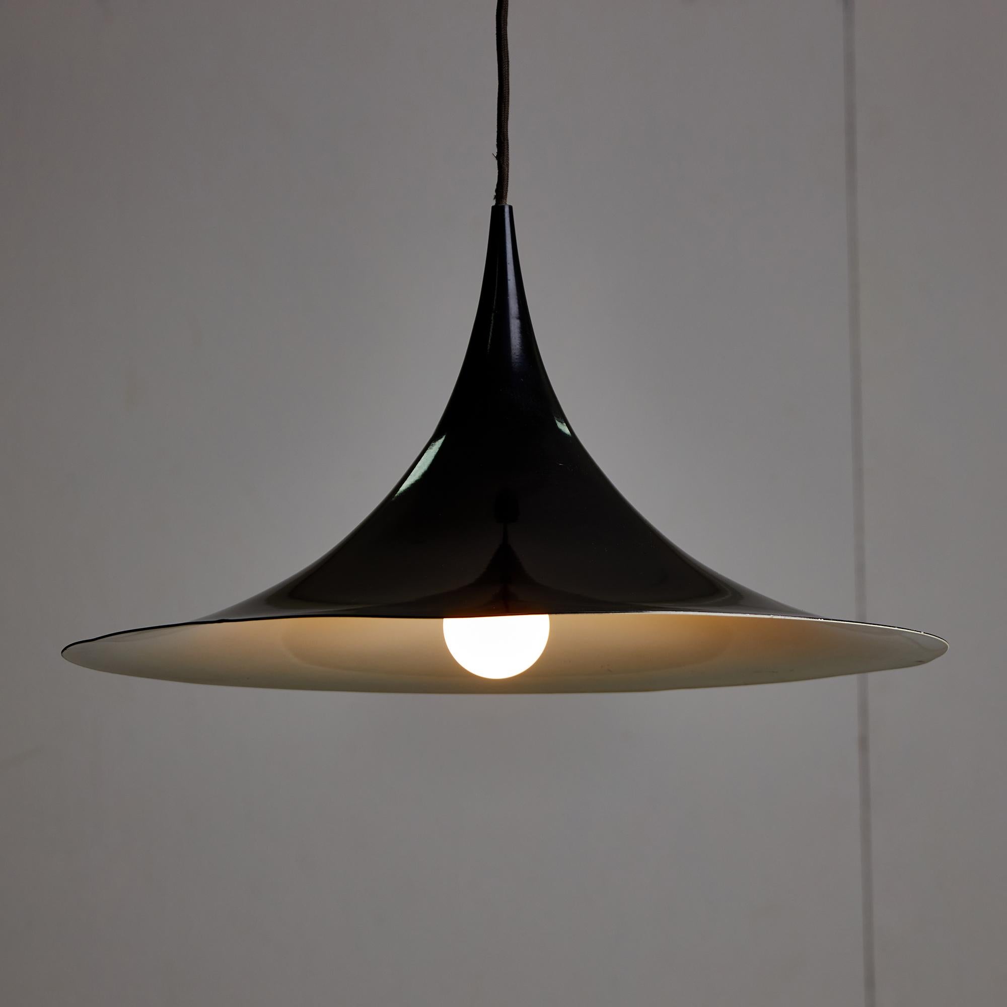 Presenta una lampada a sospensione che cattura l'essenza del design minimalista. La sua silhouette si adatta a case, uffici e spazi pubblici. Rifinita in nero, la lampada contrasta con il suo interno bianco, diffondendo una calda luce. Questa