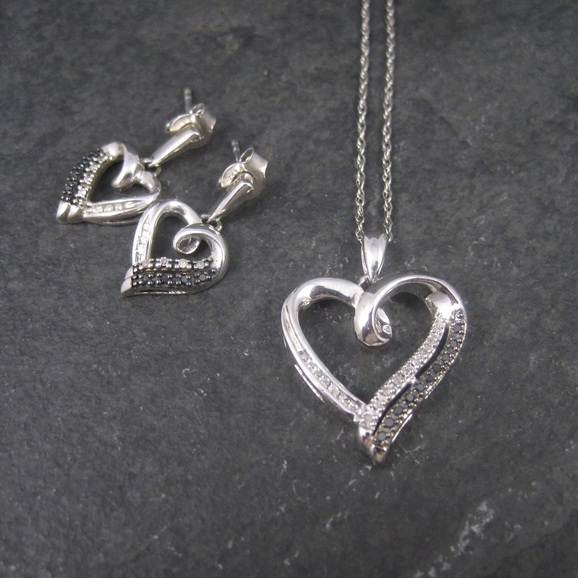 This beautiful jewelry set is sterling silver with black and white diamonds.

The pendant measures 3/4 by 1 inch.
It features an estimated .25 ctw in black and white diamonds.
Comes on an 18 inch sterling silver chain.

The earrings measure 1/2 by