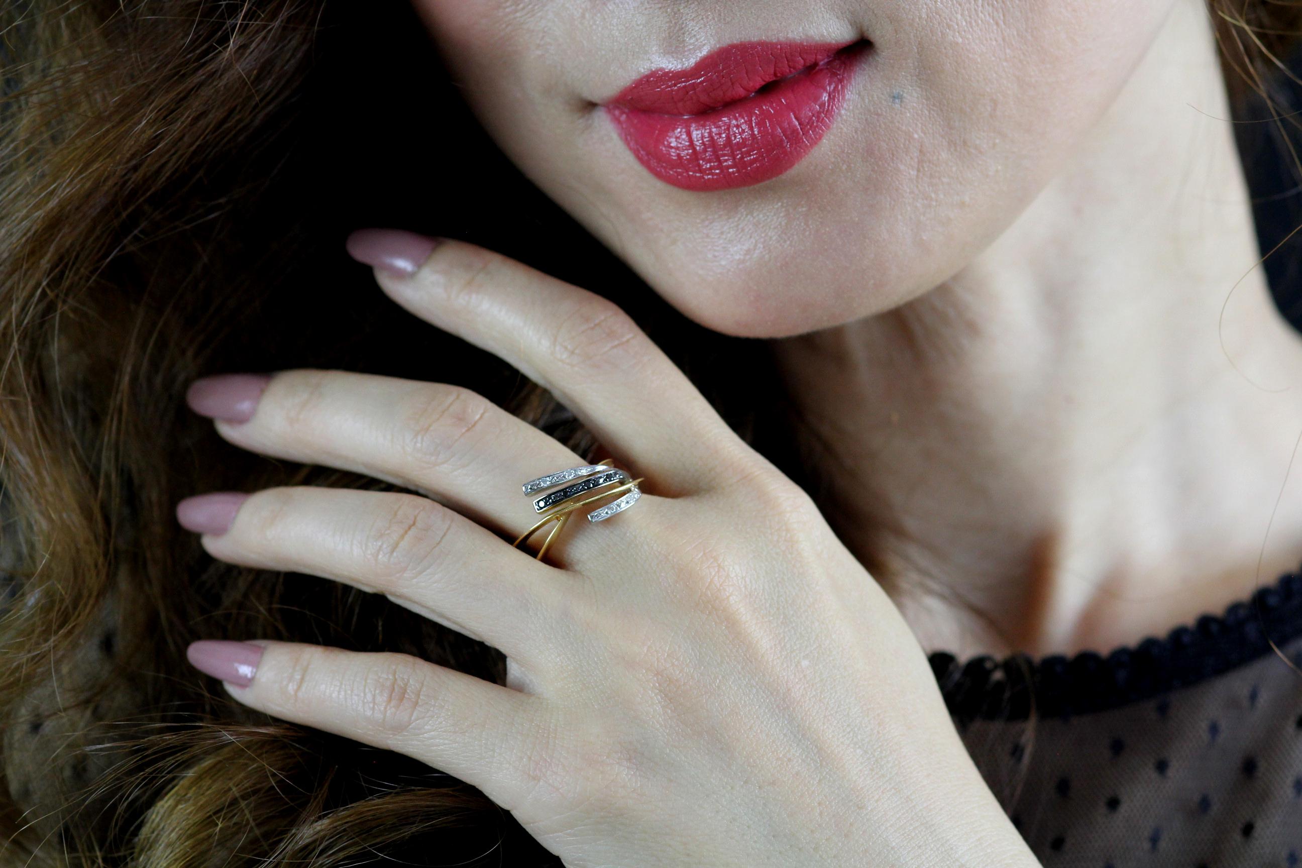 Asymmetric 18ct yellow gold, black and white diamond ring with a knife edge twisted band. A strip of black diamonds is flanked by two flashes of white diamonds for an unusual contrast. 
The outer surface on the inside of the yellow gold band is