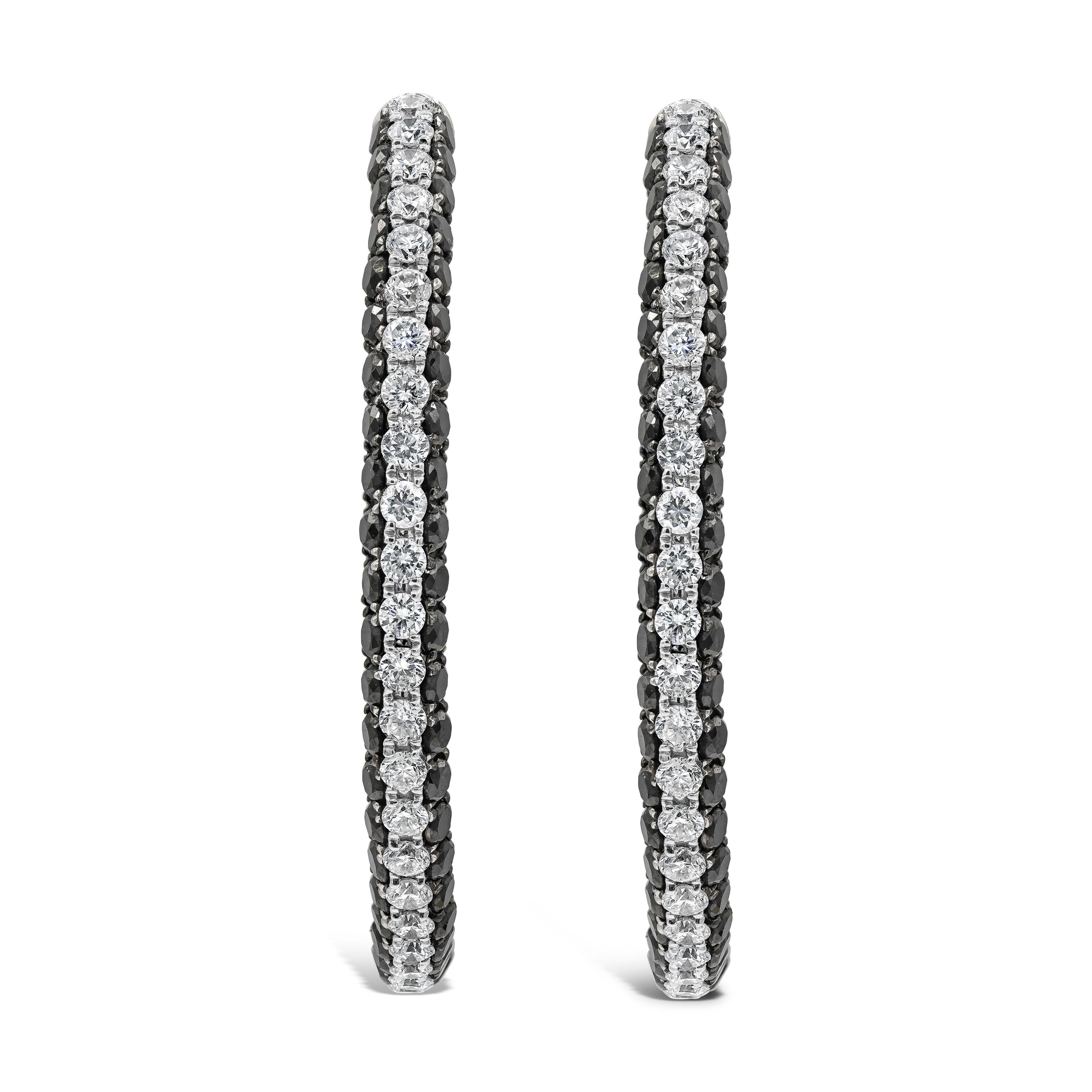 A unique and chic pair of hoop earrings showcasing A row of round brilliant white diamonds set in-between black diamonds in a micro-pave setting. Black diamonds weigh 2.60 carats total and white diamonds weigh 1.30 carats total. Made with 18K White
