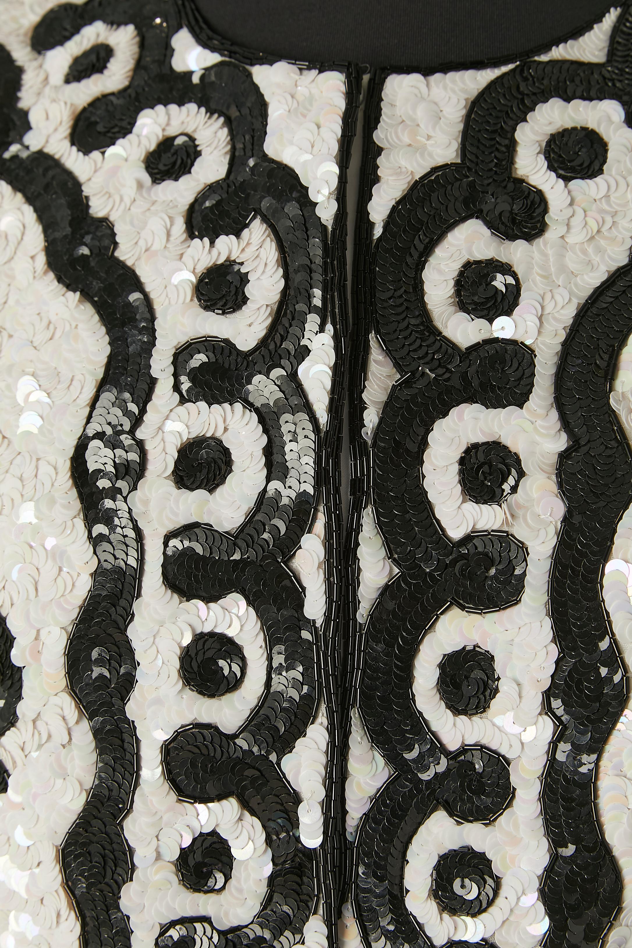 Veste de soirée noire et blanche recouverte de paillettes. Il n'y a pas d'étiquette de composition du tissu mais la doublure est probablement en rayonne. Bouton-pression caché recouvert de tissu au milieu du devant. Pad d'épaule. 
TAILLE M 