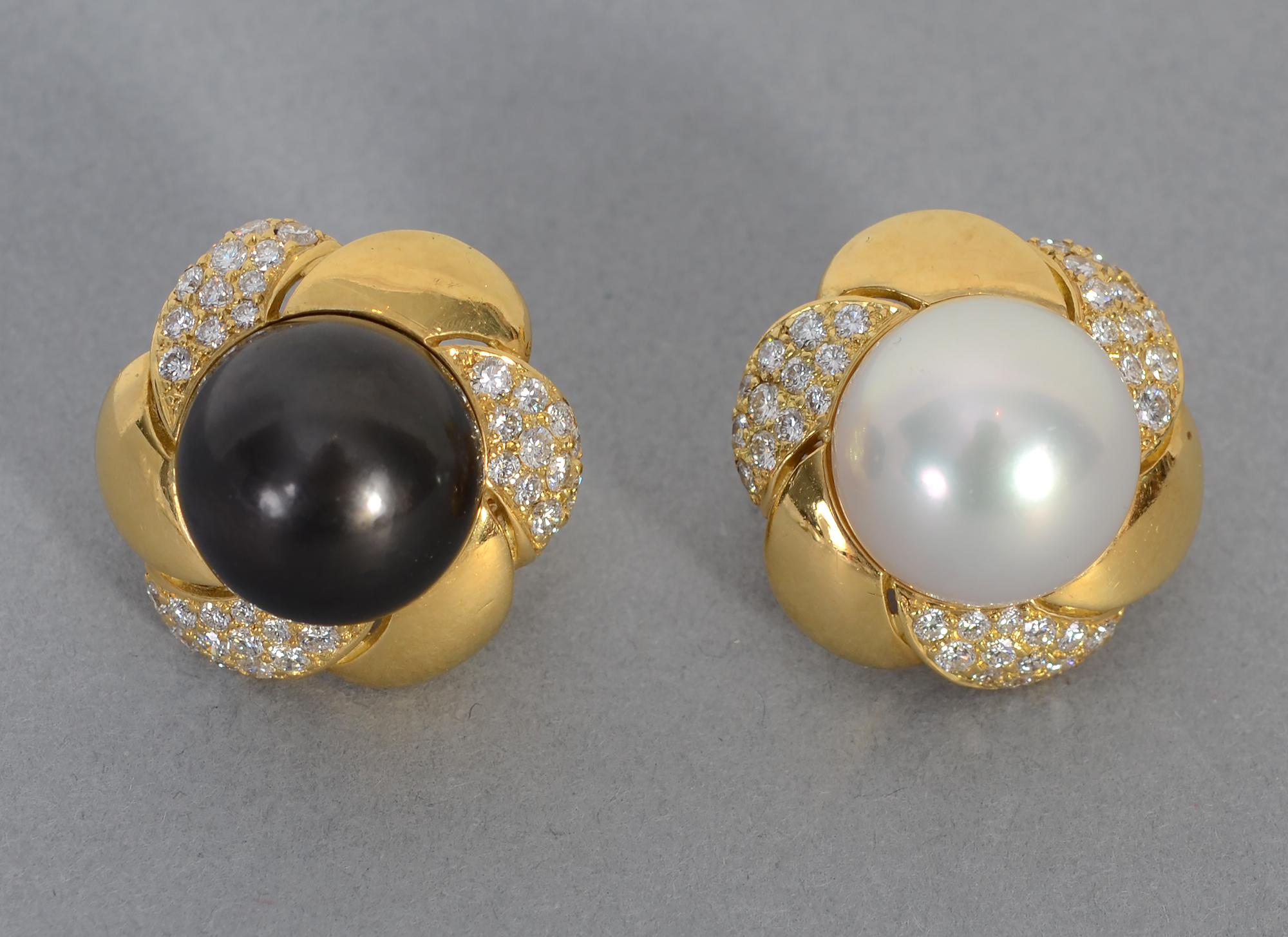 Auffallend große, schwarz-weiße Perlenohrringe, umgeben von Diamanten. Die Perlen sind jeweils 15 mm groß. Es gibt 72 runde Brillanten mit einem Gesamtgewicht von etwa 3 Karat. Gelappte Goldplättchen wechseln sich mit solchen aus Diamanten ab. Die