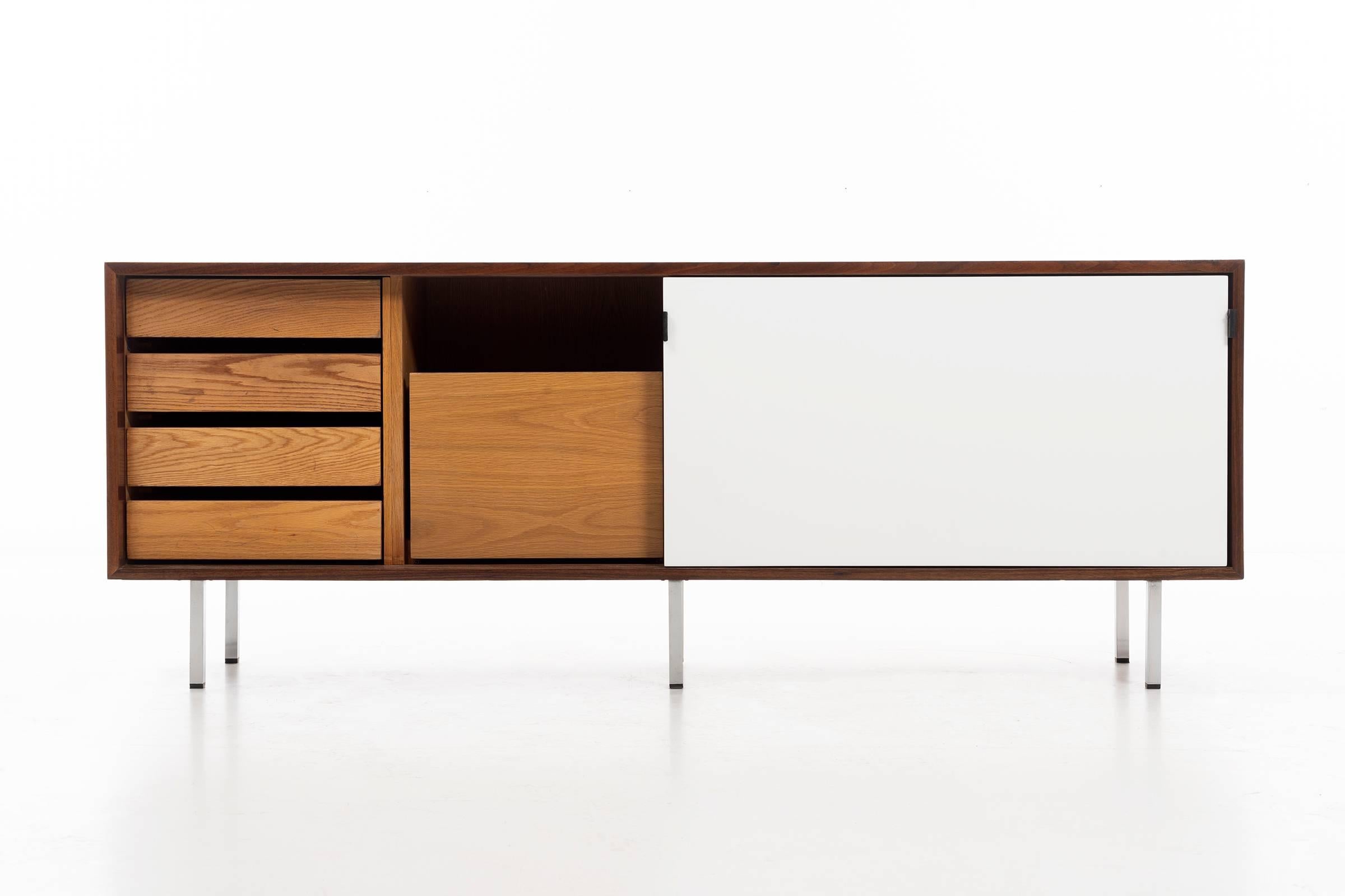 Florence Knoll credenza, walnut case with black and white lacquered doors, leather tabs as pulls, inside case four compartments: Four drawers, file drawer, other side two compartments, one side pullout drawer and open storage.
 