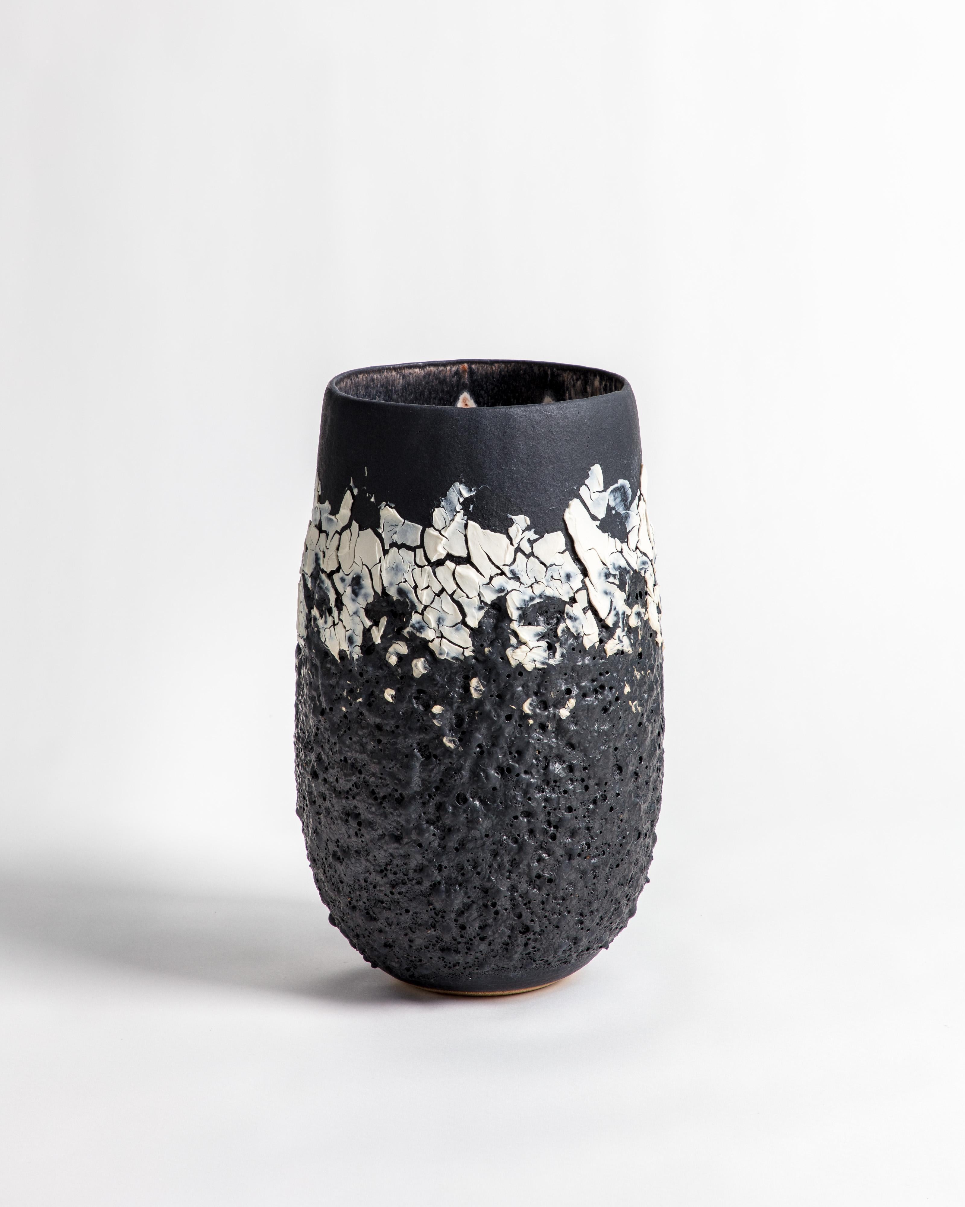 A black bubble lava textured volcanic open vessel with black and white glaze and markings. Made from textured stoneware clay and porcelain engobe.

Inspiration for the piece comes from the clay itself and the chemical relationships that glaze and