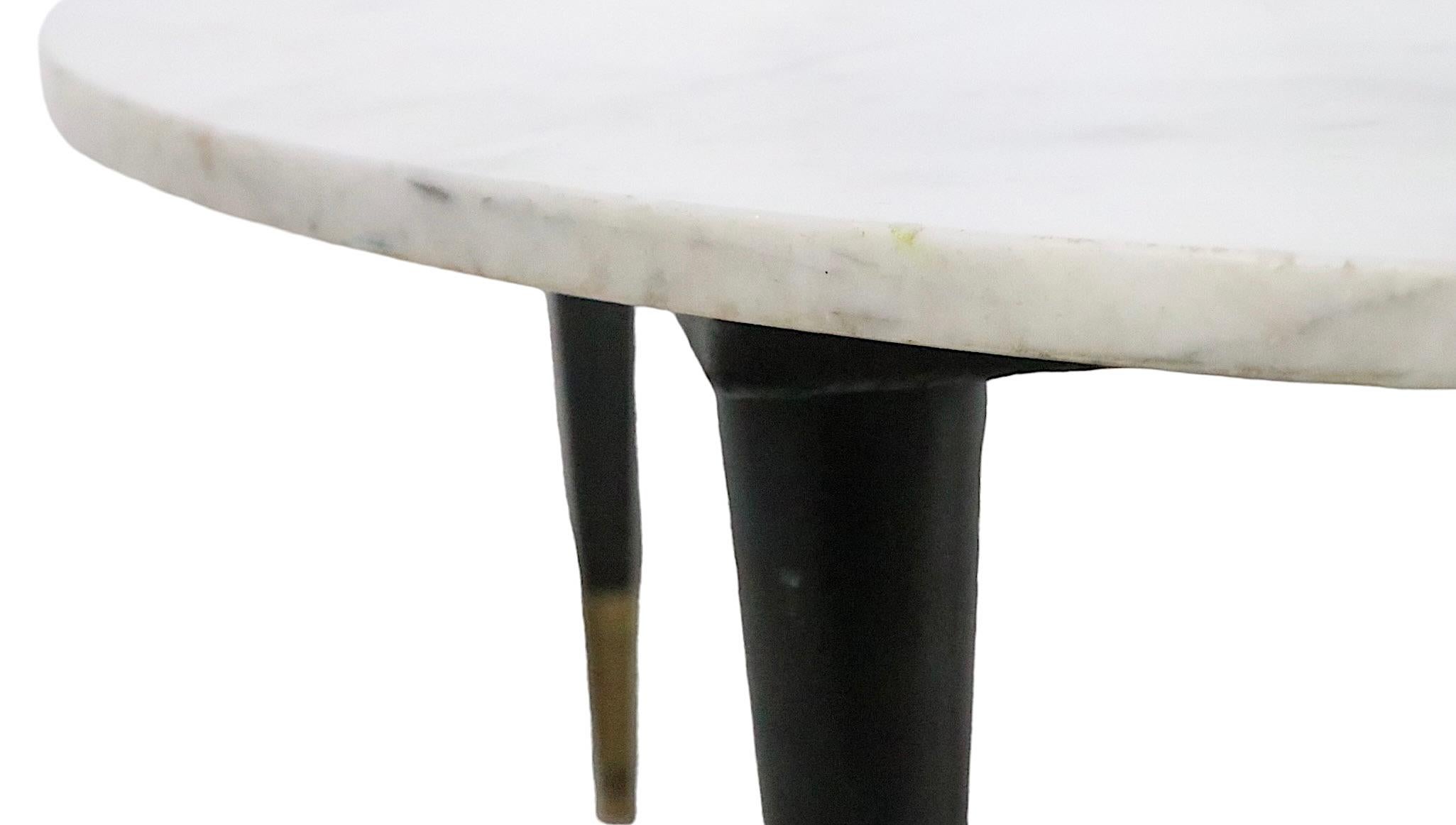 Chic architectural marble top coffee table with off white marble on black tapered pole legs with brass ferrule feet. This classic Mid Century coffee cocktail table is in very good, original, clean and ready to use condition, showing only light