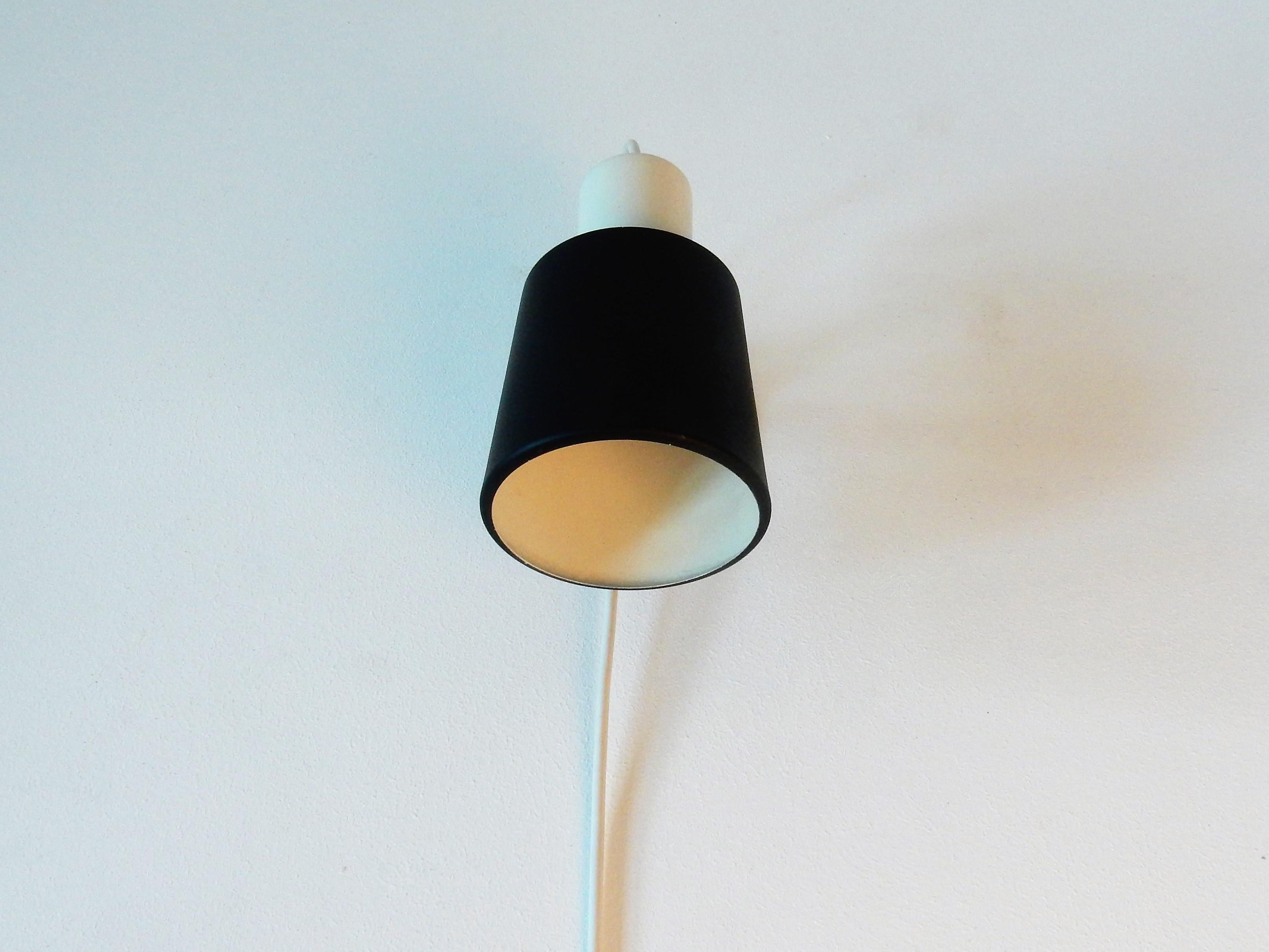 This nice and smart black and white Anvia wall lamp is a true beauty. It was most likely designed by Jan Hoogervorst in the 1960s and is documented in the Anvia catalogue as model 7062. The lamp can be turned in all directions to create a nice