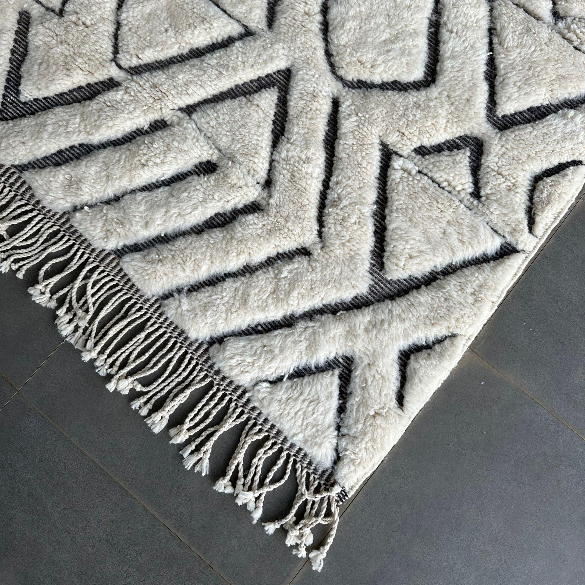 Introducing the Atlas Allure, a captivating black and white Moroccan rug that adds a touch of modern elegance to any space. This stunning rug features a pristine white base adorned with a black, textured tribal design, creating a striking and