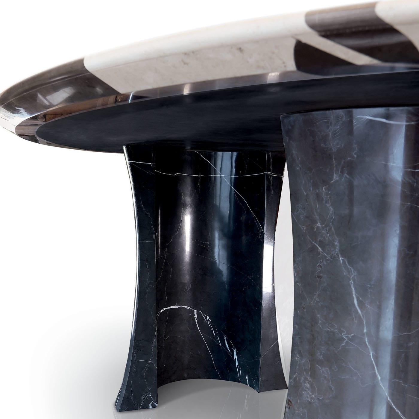 This oval marble table is a stately and sculptural piece whose visual charm never fails to impress. The dynamic geometric-inspired pattern adorning the top results form a masterful inlay work featuring fine Crema Luna and Pietra Gray marbles, its