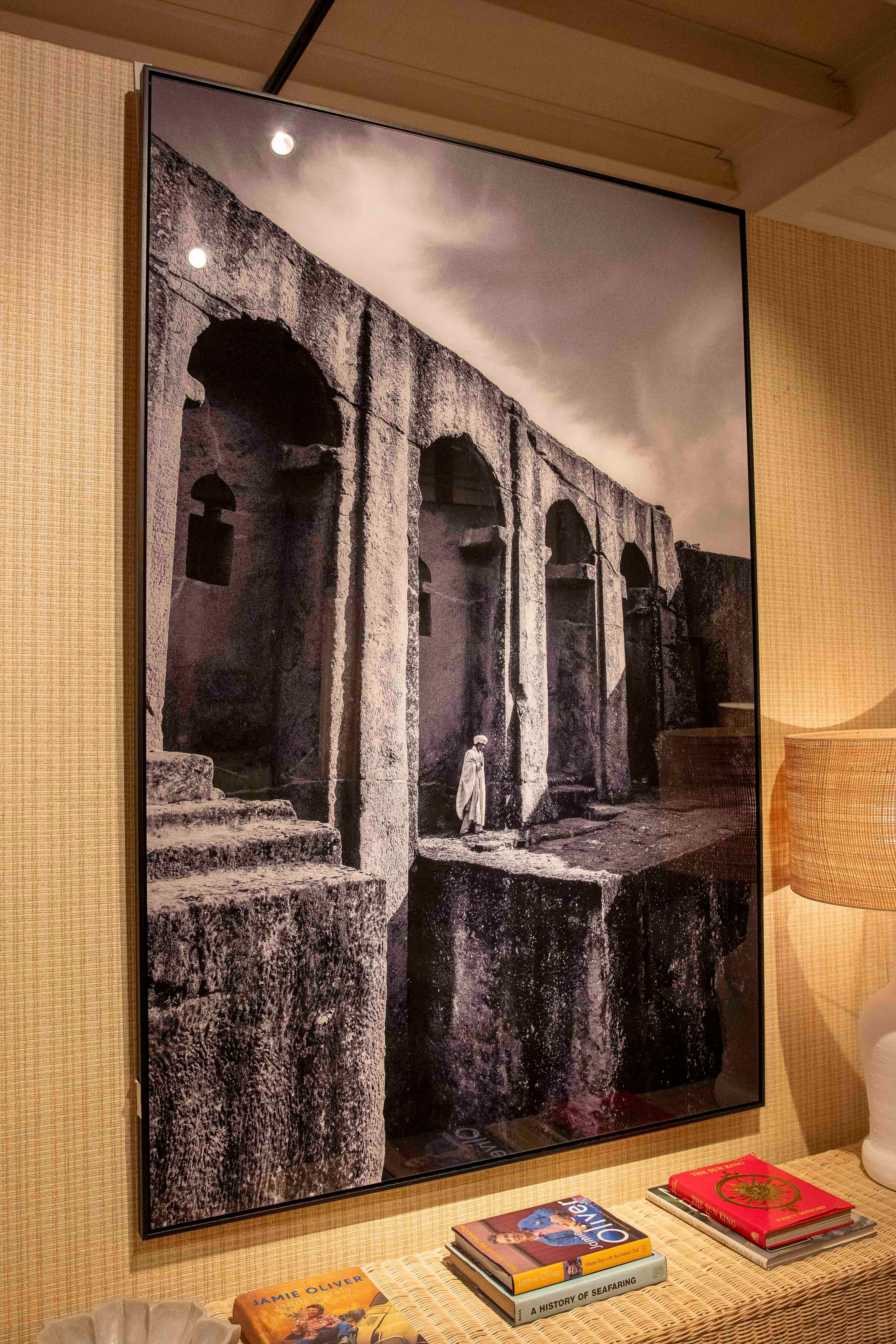 A striking black and white photograph depicting one of the famous monolithic churches of Lalibela, Ethiopia, declared a UNESCO World Heritage Site. The image captures the monumentality of the architecture carved directly into the volcanic rock, with