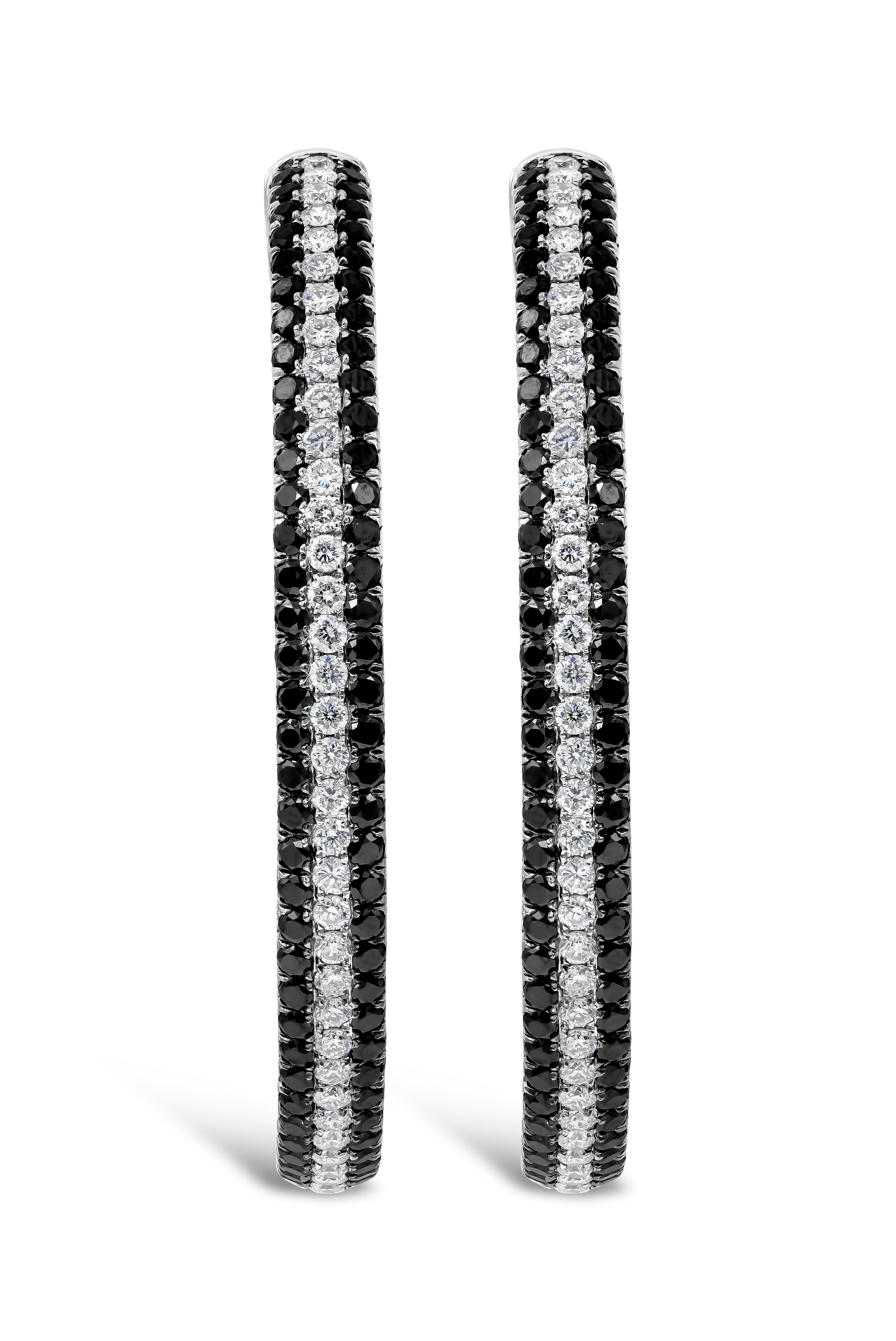 A unique and well crafted pair of hoop earrings showcasing alternating pave set black and white round diamonds set in the inside and outside. Black round diamonds weighs 6.30 carat total, White round diamonds weighs 3.30 carat total. Approximately 2