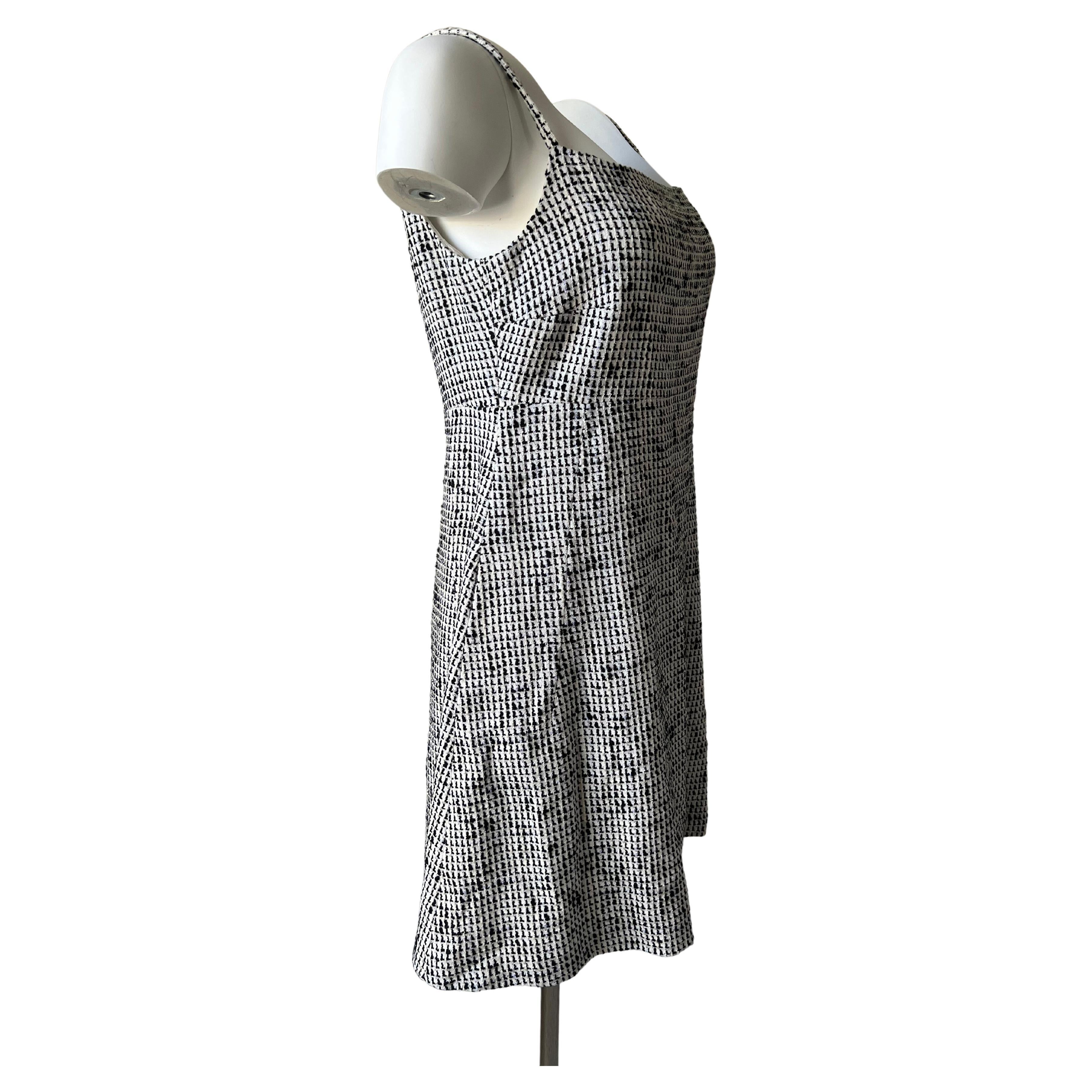 Pretty dress in black and white cotton tweed, inclusion of glossy bluish line, pretty silver bonton interlacing of black leather and Chanel logo in the center, Collection 2010.
