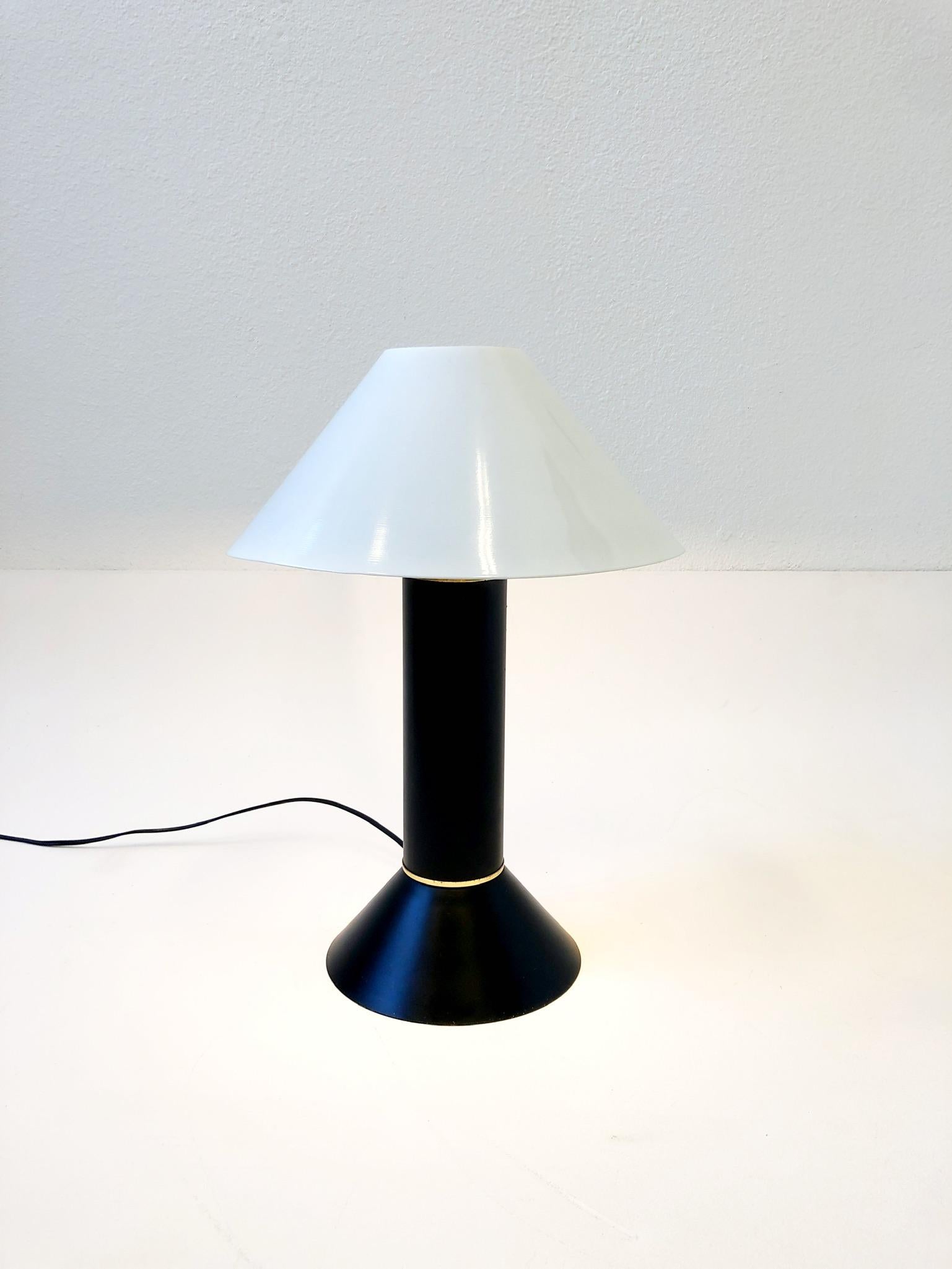 1980’s Postmodern black and white powdered coated table lamp by Ron Rezek. 
In beautiful vintage condition. 
It take one regular edition 75w max lightbulb. 
Measurements: 12.5” diameter, 18” high. 
Base- 7.75” diameter.