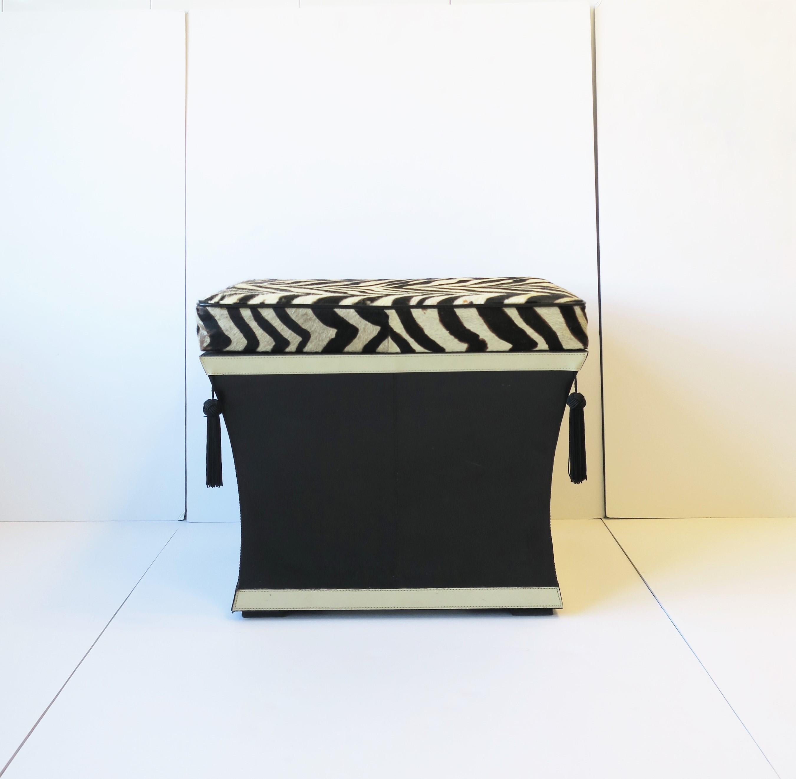 A black and white zebra hide bench/stool/ottoman with storage and tassel design, circa late-20th century, 1980s-1990s. Bench, by Bombay Furniture Co., is rectangular in shape, has authentic animal zebra hide seat cushion with black welting, black