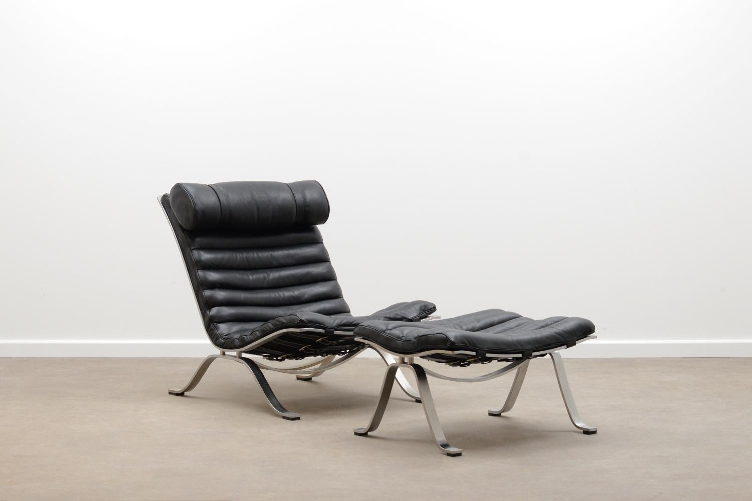 Black “Ari” chair and ottoman by Arne Norell for Norell möbel AB. This is the price winning flagship model of Arne Norell. Brushed steel frame, Leather belts and buffalo leather seat and cushion. The cushion can be removed or adjusted in height with