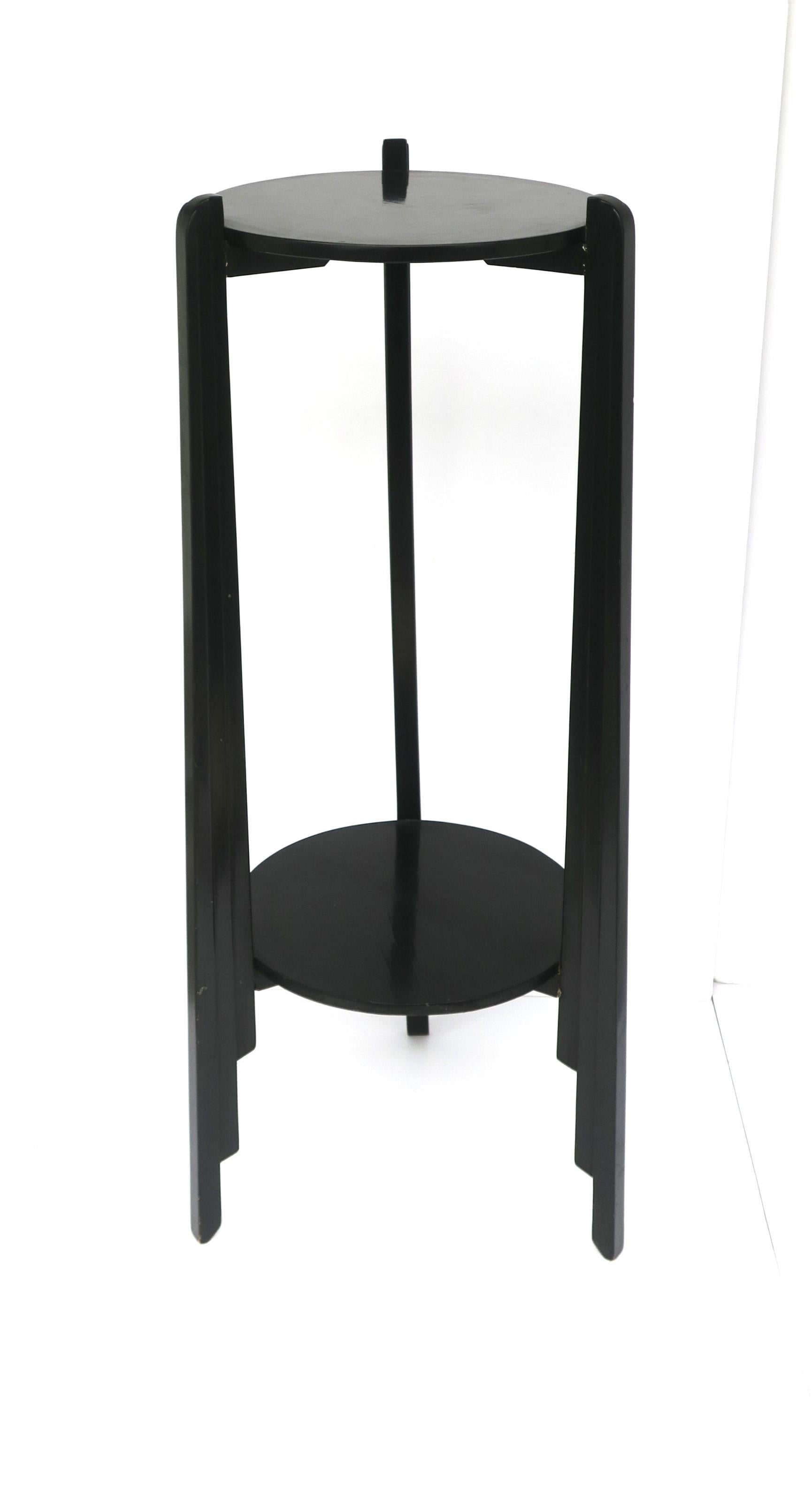 A black gloss column pedestal pillar stand with lower shelf, Art Deco period, circa early to mid-20th century. Column is wood with a black gloss finish, tri-pod legs with Art Deco detail, attached to a 12