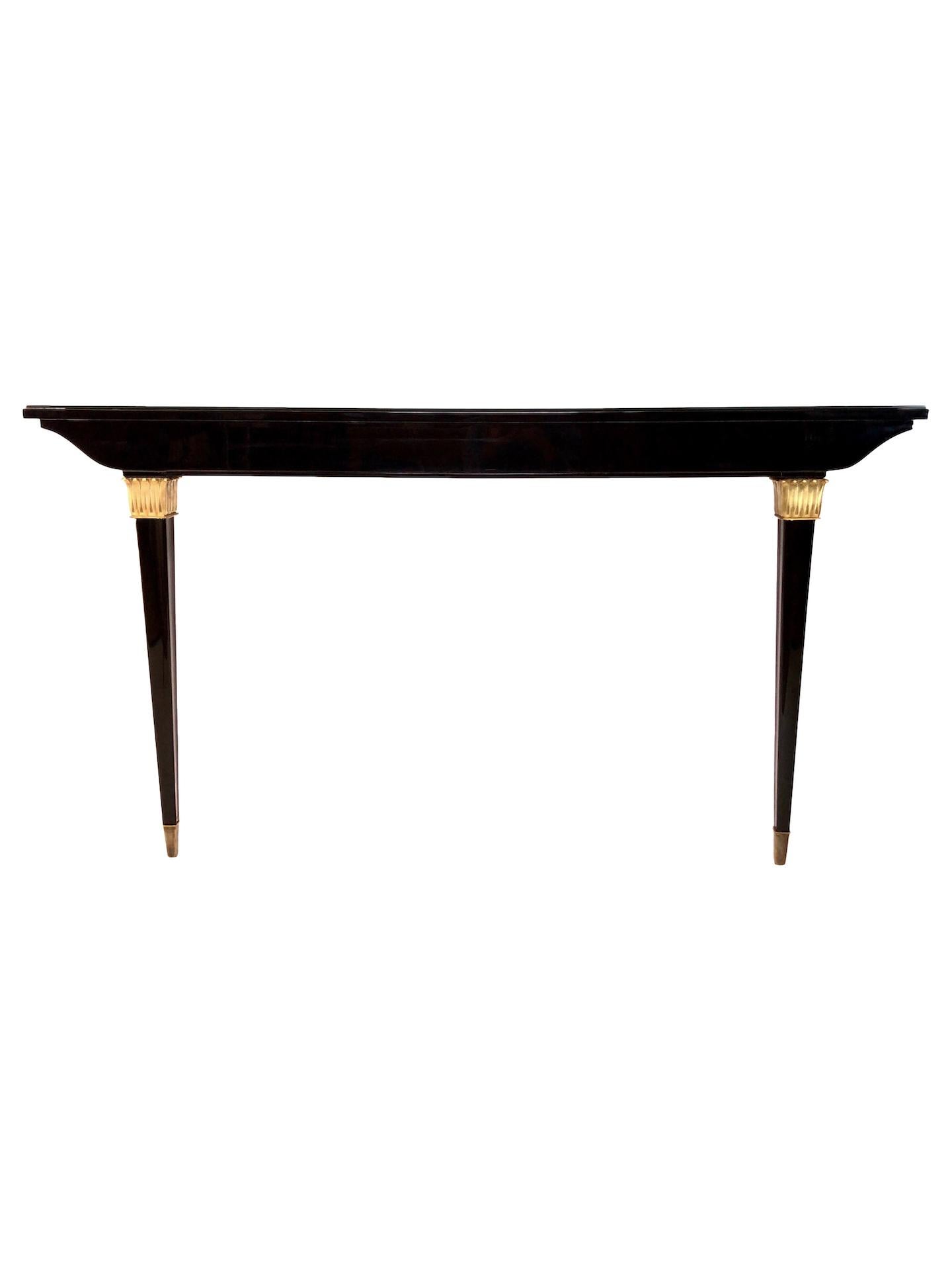 The combination of black piano lacquer and golden applications gives this console table its royal charm.
Original French Art Deco, circa 1935.
High gloss black piano lacquer
Black glass tabletop to protect the lacquer for daily use
Brass sabots