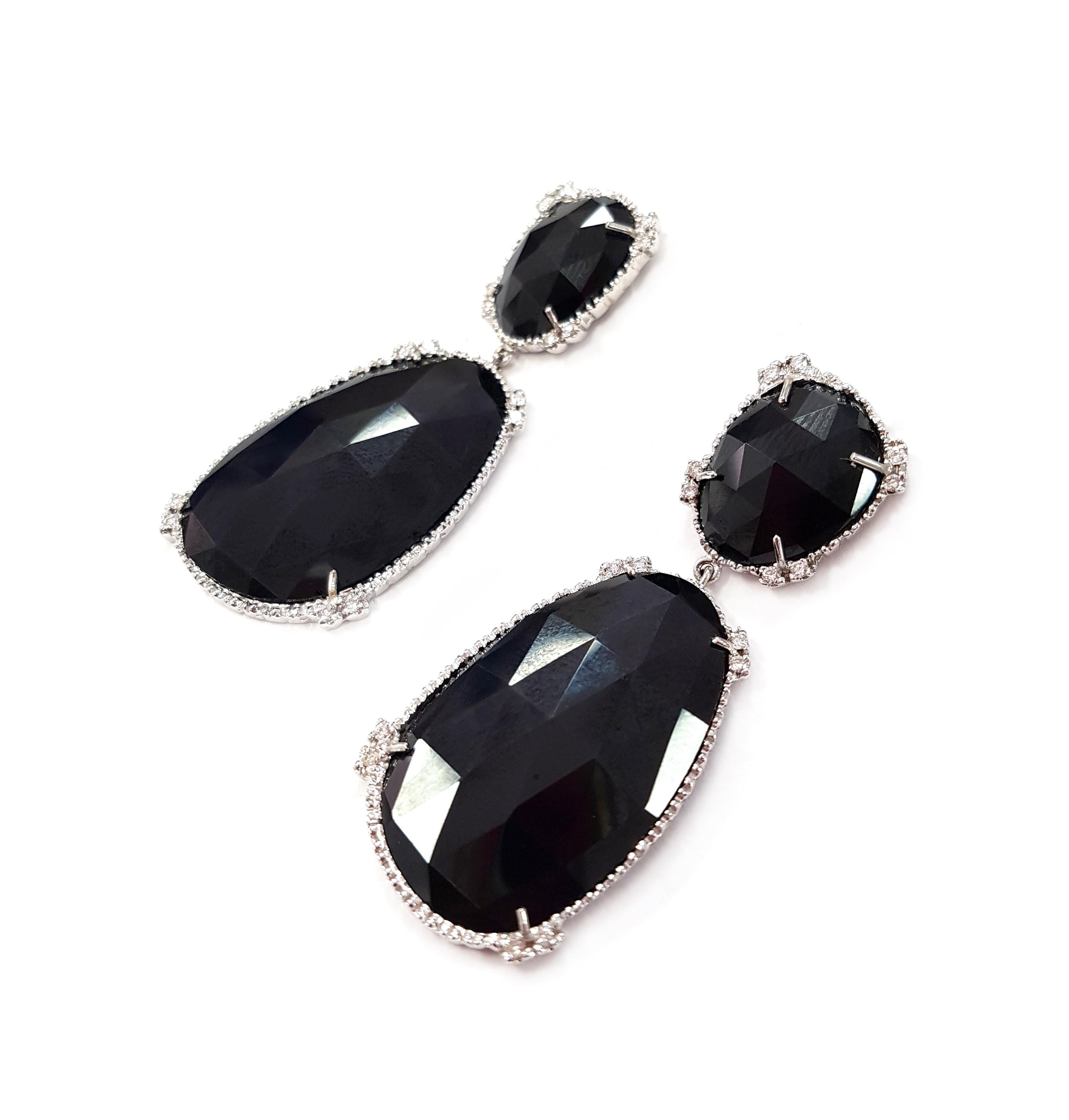 A stunning pair of post-back 18-karat white gold pendant earrings in the style of Art Deco. The high-lustre, faceted black stones are set in white gold and four pairs of small diamonds.

They hang about 5 centimetres long and weigh (combined) 16.8