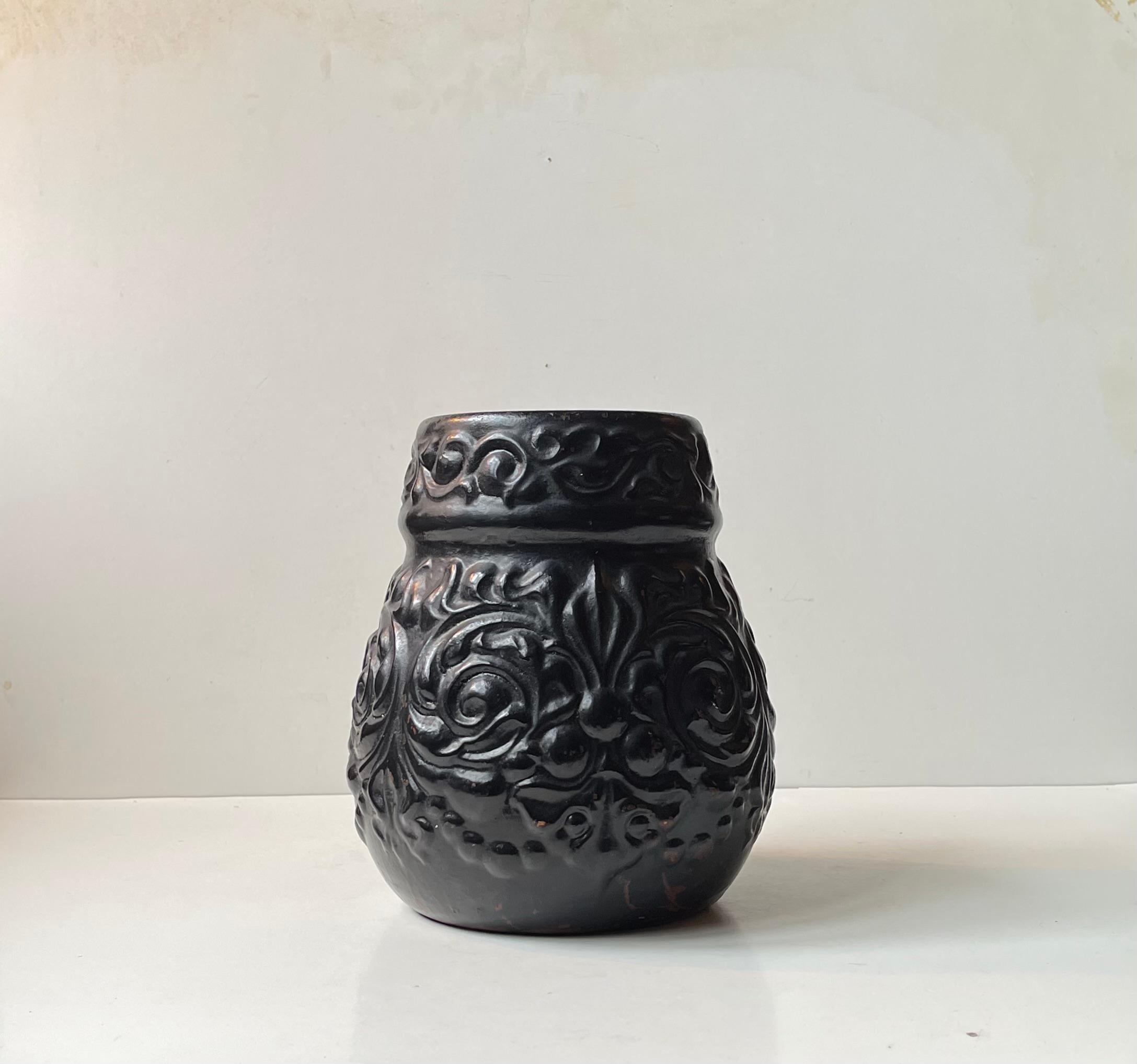 Unusual relief earthenware vase with floral patterns. Black paint over maroon paint. Designed and manufactured by Knabstrup in Denmark during the 1920s. Similar in appearance to designs by Kähler, Ipsens Enke and early Søholm. 

Marked: 316 beneath