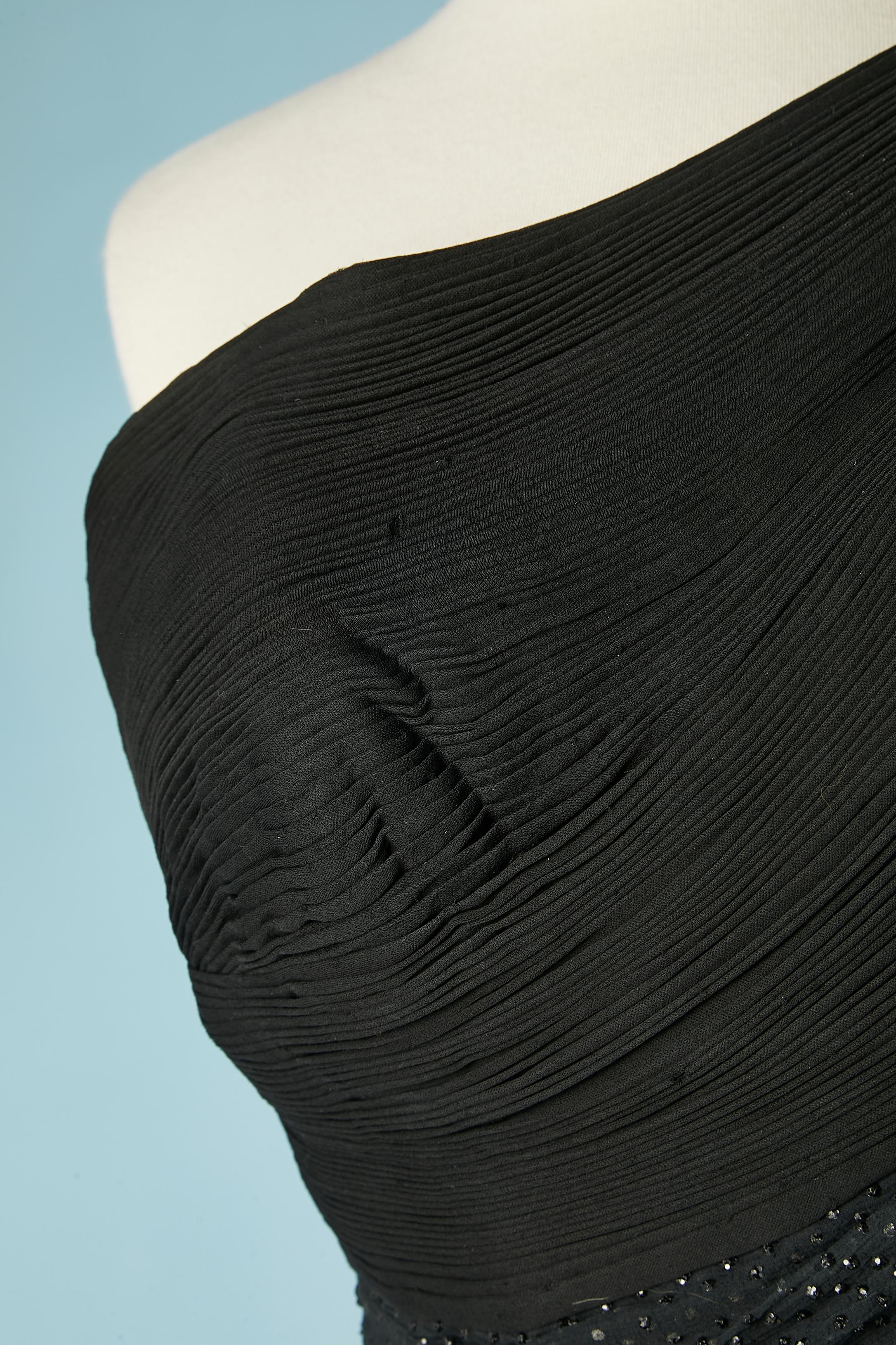 Schwarzes asymmetrisches Cocktailkleid mit Falten und Drapierungen. Die Falten sind aus Seidenjersey gefertigt. Der zweite Stoff ist Seidenchiffon mit Glitzern. Bügel-BH innen mit Samtbändern paspeliert. Entbeint. Rillenförmiges Taillenband. 
SIZE