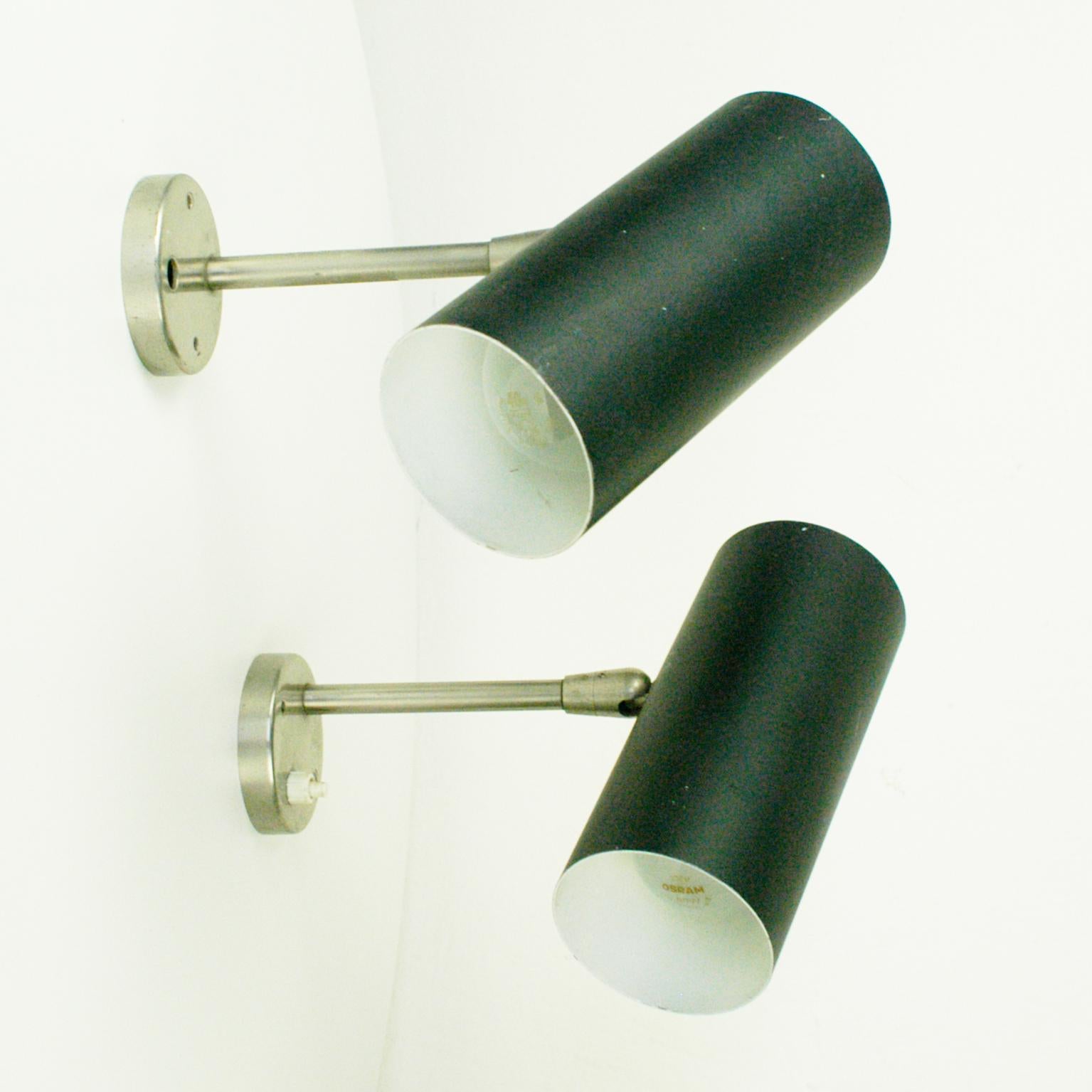This minimalistic and pure Austrian Midcentury zylindrical pair of wall lights with was designed and manufactured by J. T. Kalmar in the 1960s in Vienna Austria.
They feature zylindtical black lacquered metal shades on a stainless steel base. The