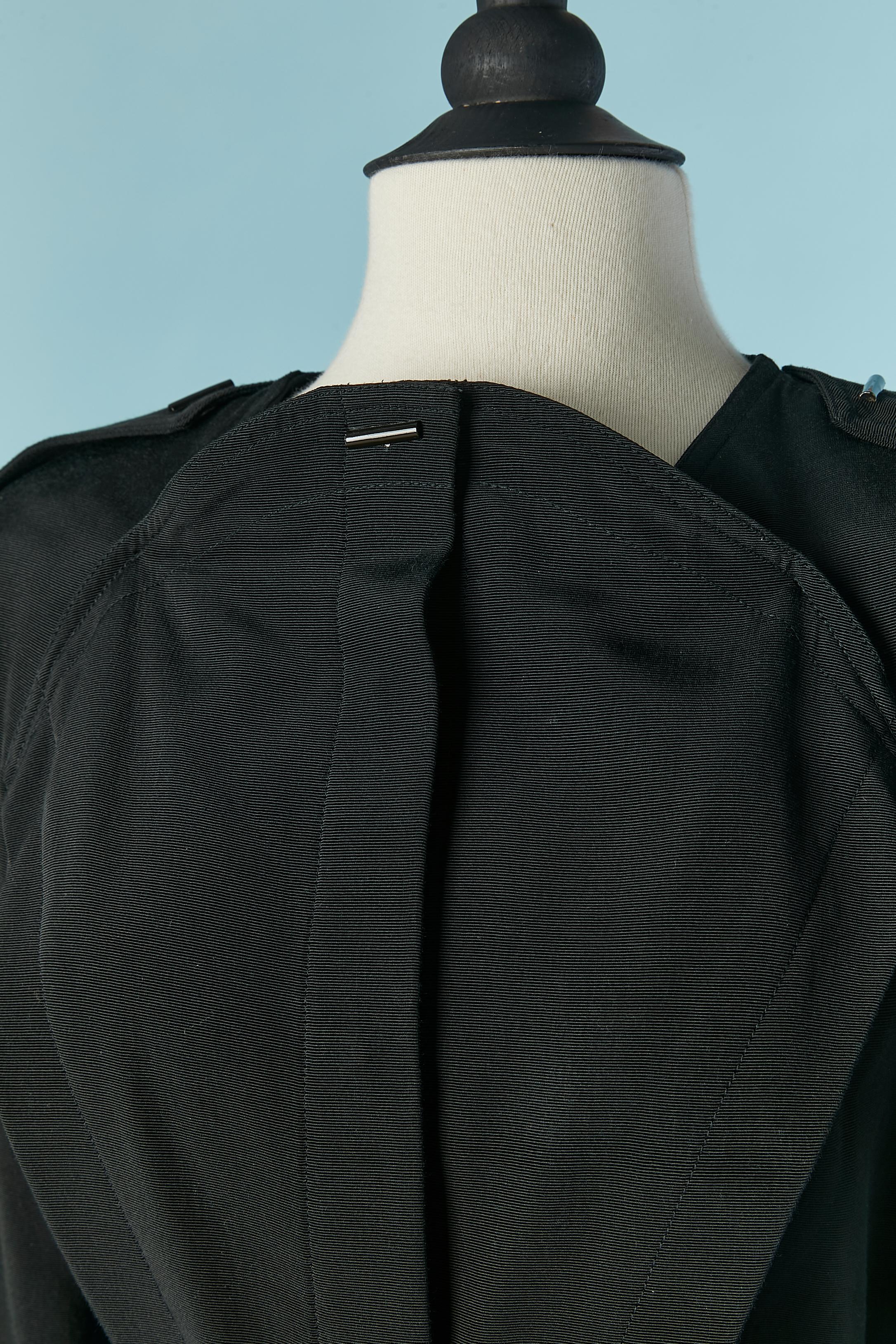 Black backless long jacket . No fabric composition tag but probably rayon. 
Hidden snap closure on the middle front. Belt in the same fabric with metal buckle closure. Shoulder pad. Pocket on both side. Large belt-loop on the middle back. 
SIZE 38