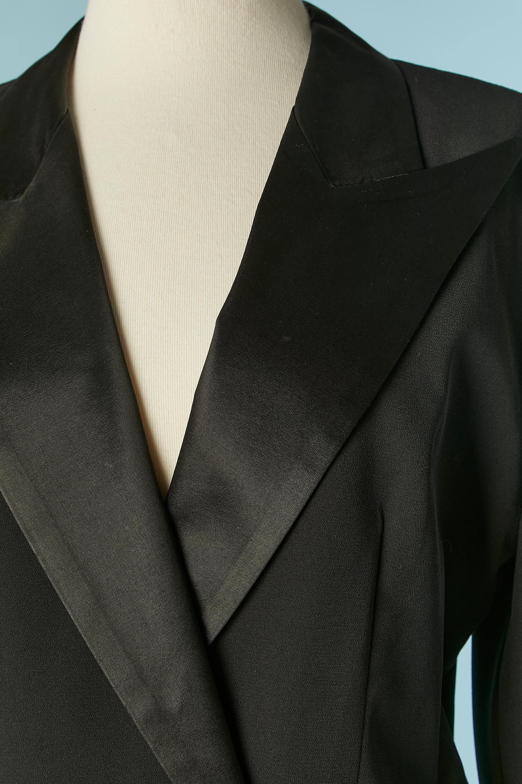 Traje Tudexo negro sin espalda, de crepé de poliéster y botones de strass. Composición del forro: acetato. 
Espalda abierta con medio cinturón. 
Bolsillos decorativos en ambos lados. 
TALLA L 

