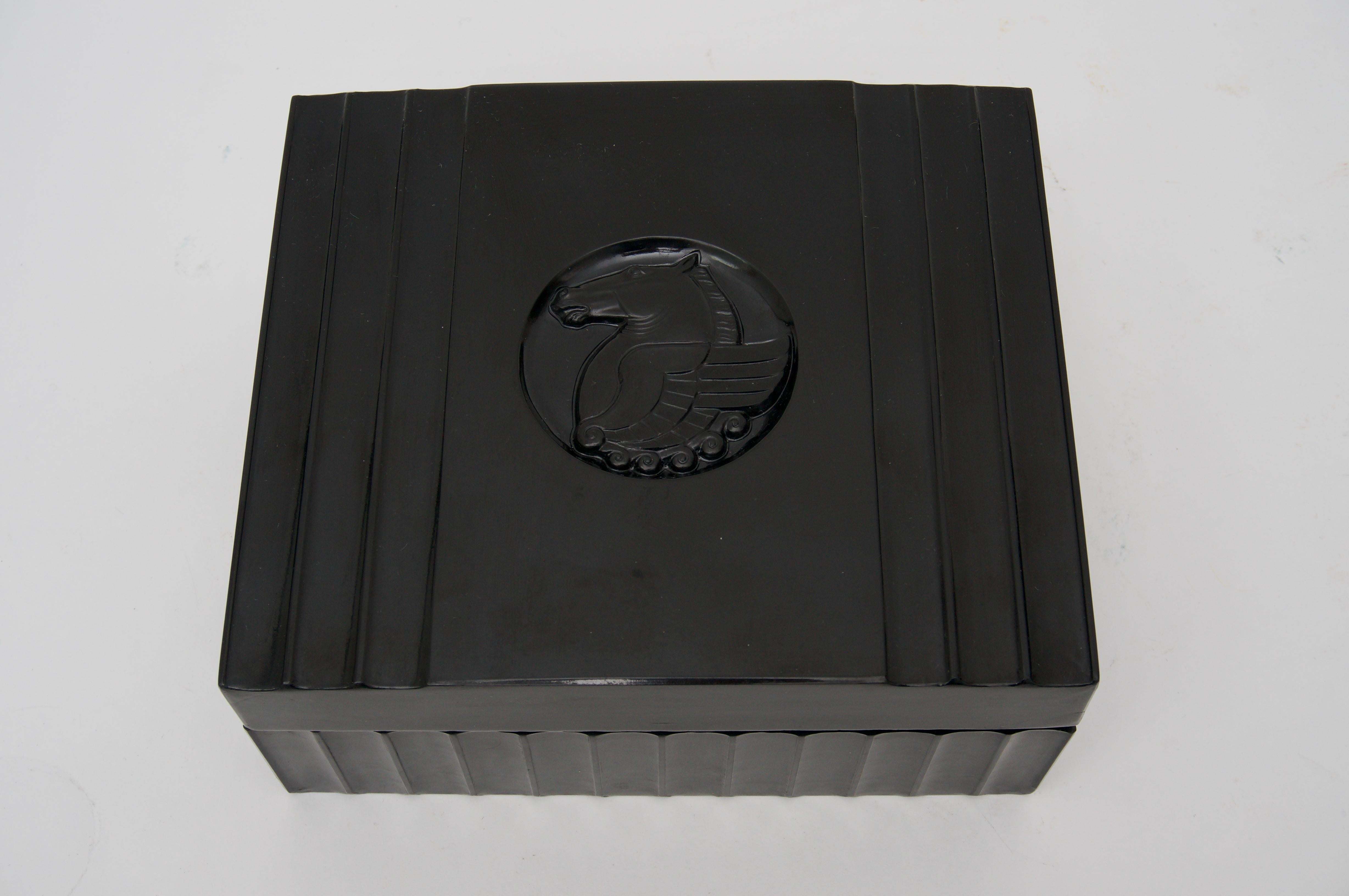 This stylish large-scale American Art Deco bakelite box dates to the late 1920s to the early 1930s. The piece is detailed with convex fluted sides and lid with a central medallion of Pegasus.

FYI
Usually depicted as pure white, Pegasus is a