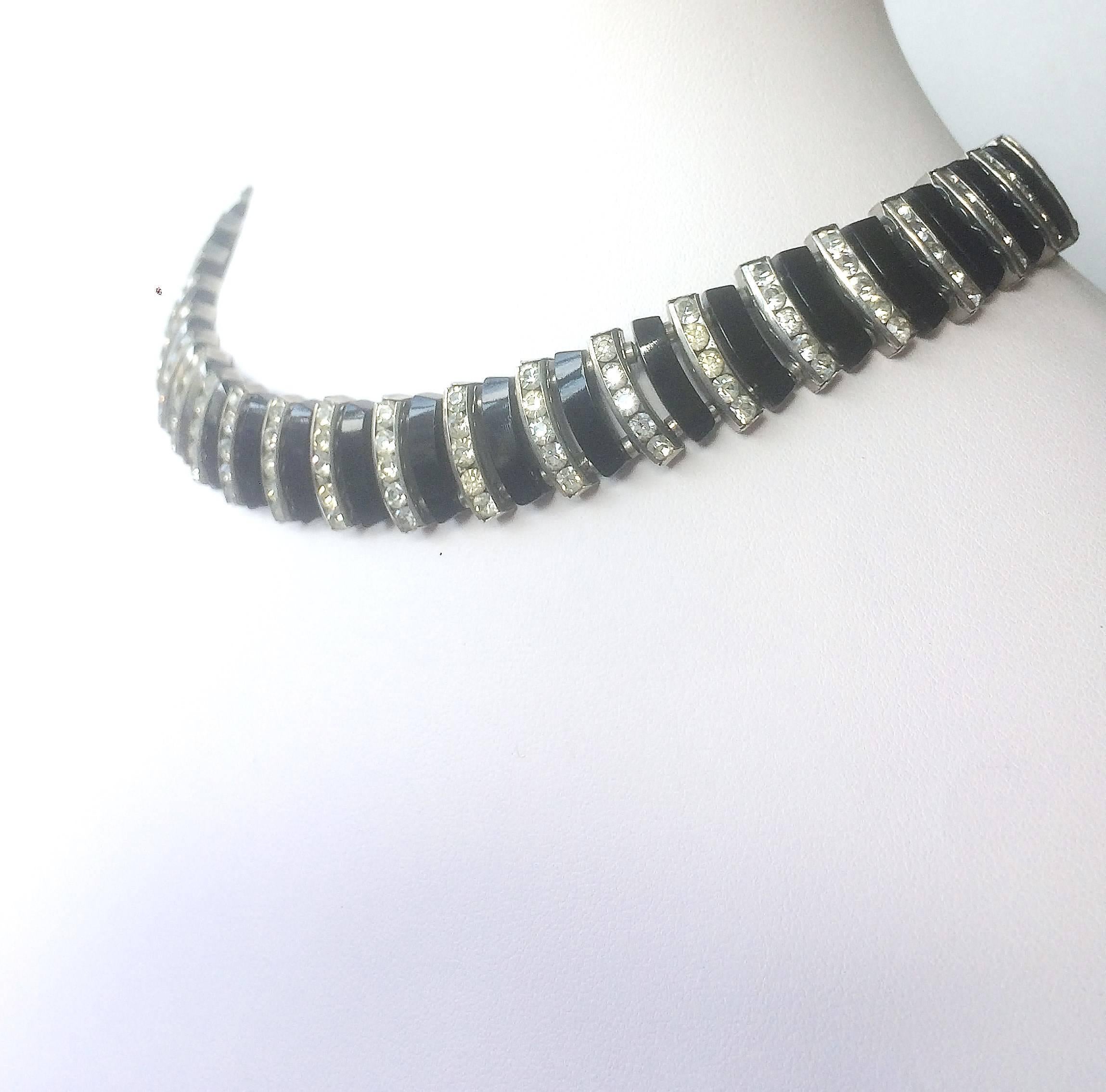 High in Art Deco style and colourway, this black Bakelite and clear paste necklace is unsigned but made by Esha Randel, in Germany in the 1930s. This is choker length, sitting at the base of the neck, beautifully made and engineered.