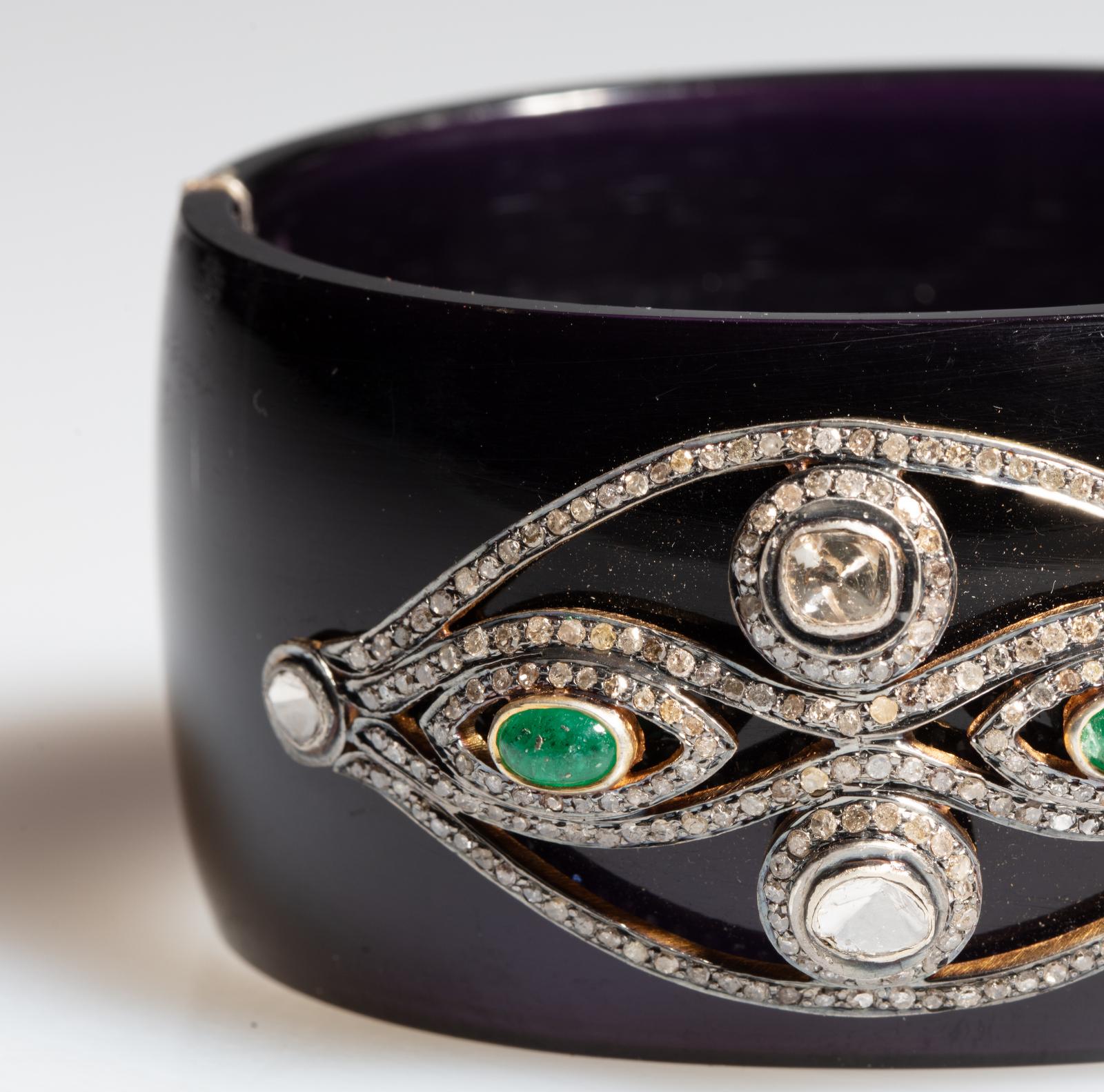 A black Bakelite cuff bracelet with an evil eye motif (offering protection from evil) of rose cut diamonds, oval cabochon emeralds surrounded in brilliant-cut pave-`set diamonds all set in sterling silver.  A sterling silver push clasp with two