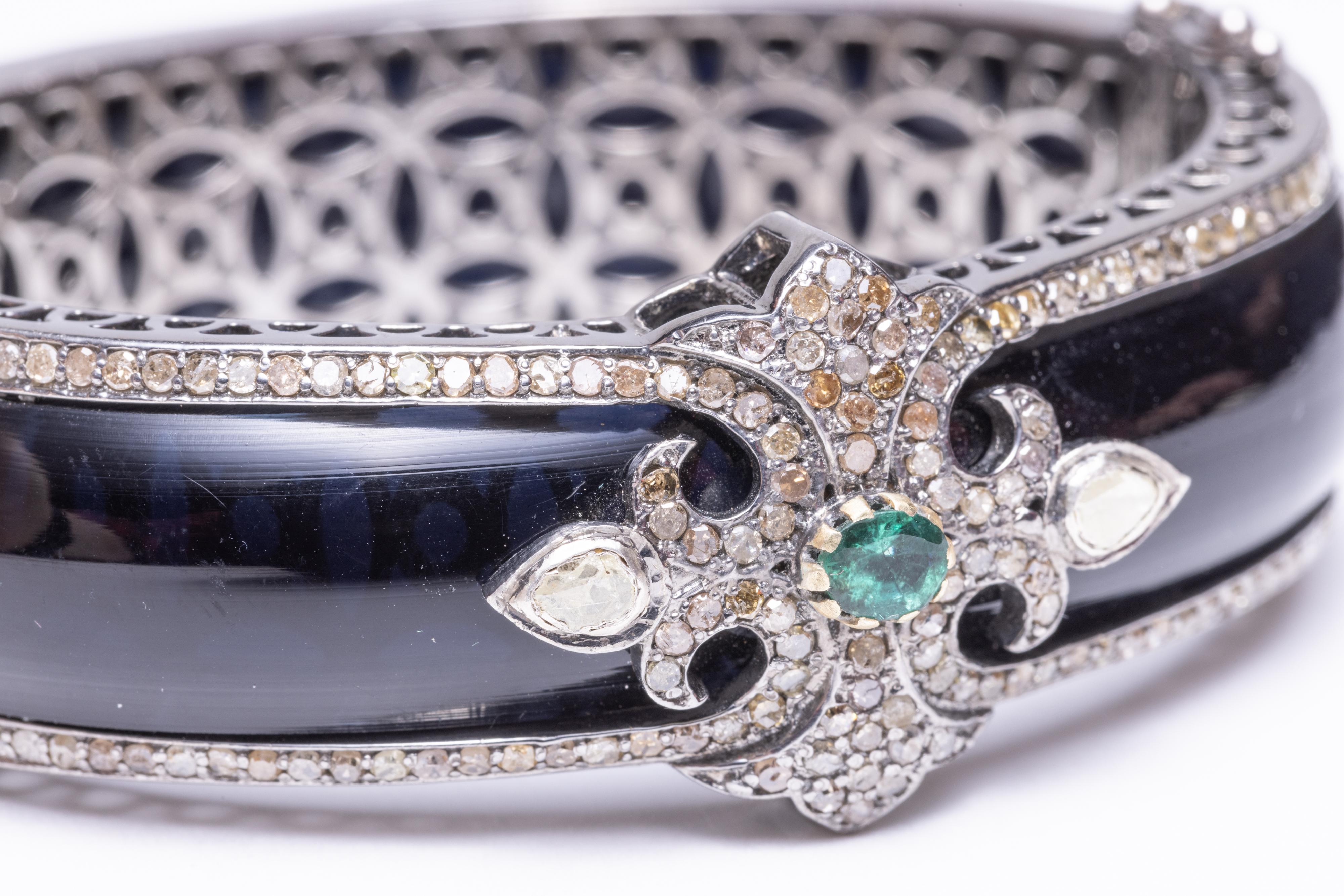 A stunning cuff bracelet in black Bakelite bordered on both sides with pave` set diamonds.  The top features additional pave` set diamonds with an oval, faceted emerald and two rose-cut diamonds on each side.  Inside circumference is 6 1/8th inch. 