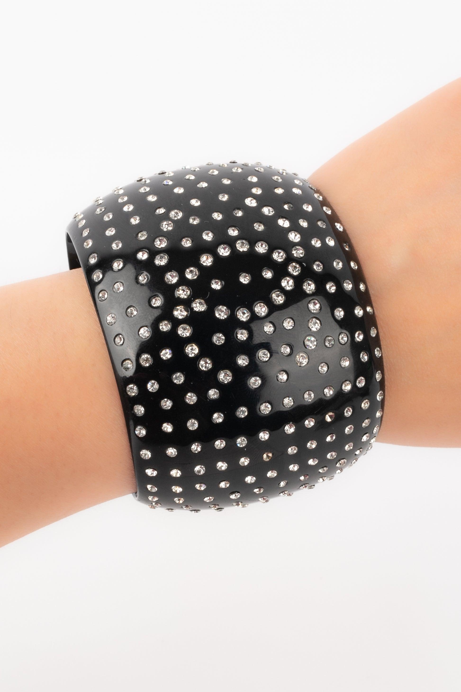 Chanel - (Made in France) Bracciale in bachelite nera con strass. Collezione Autunno-Inverno 1995.

Informazioni aggiuntive:
Condizioni: Ottime condizioni
Dimensioni: Circonferenza: 14 cm - Apertura: 3 cm - Larghezza: 5,5 cm
Periodo: 20°