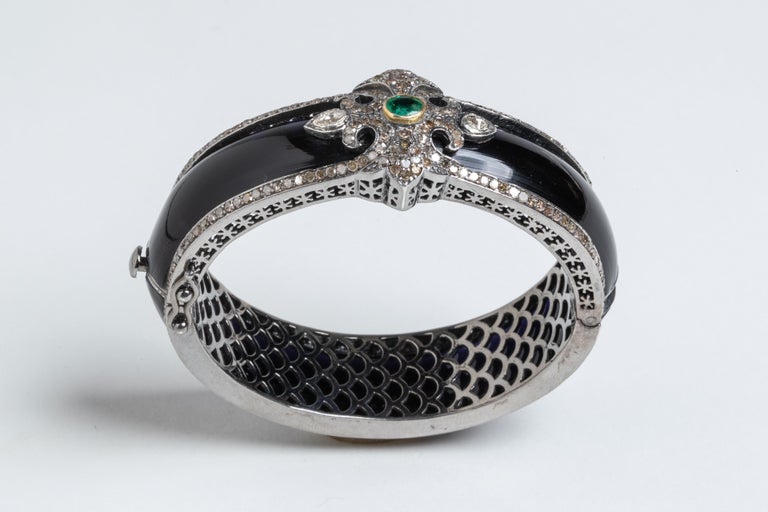 A close fitting fascinating bracelet of black bakelite bordered with pave` set diamonds in sterling silver.  The top features more pave`-set diamonds, two rose-cut diamonds and a center, faceted oval emerald.  Push clasp with two safeties.  Inside