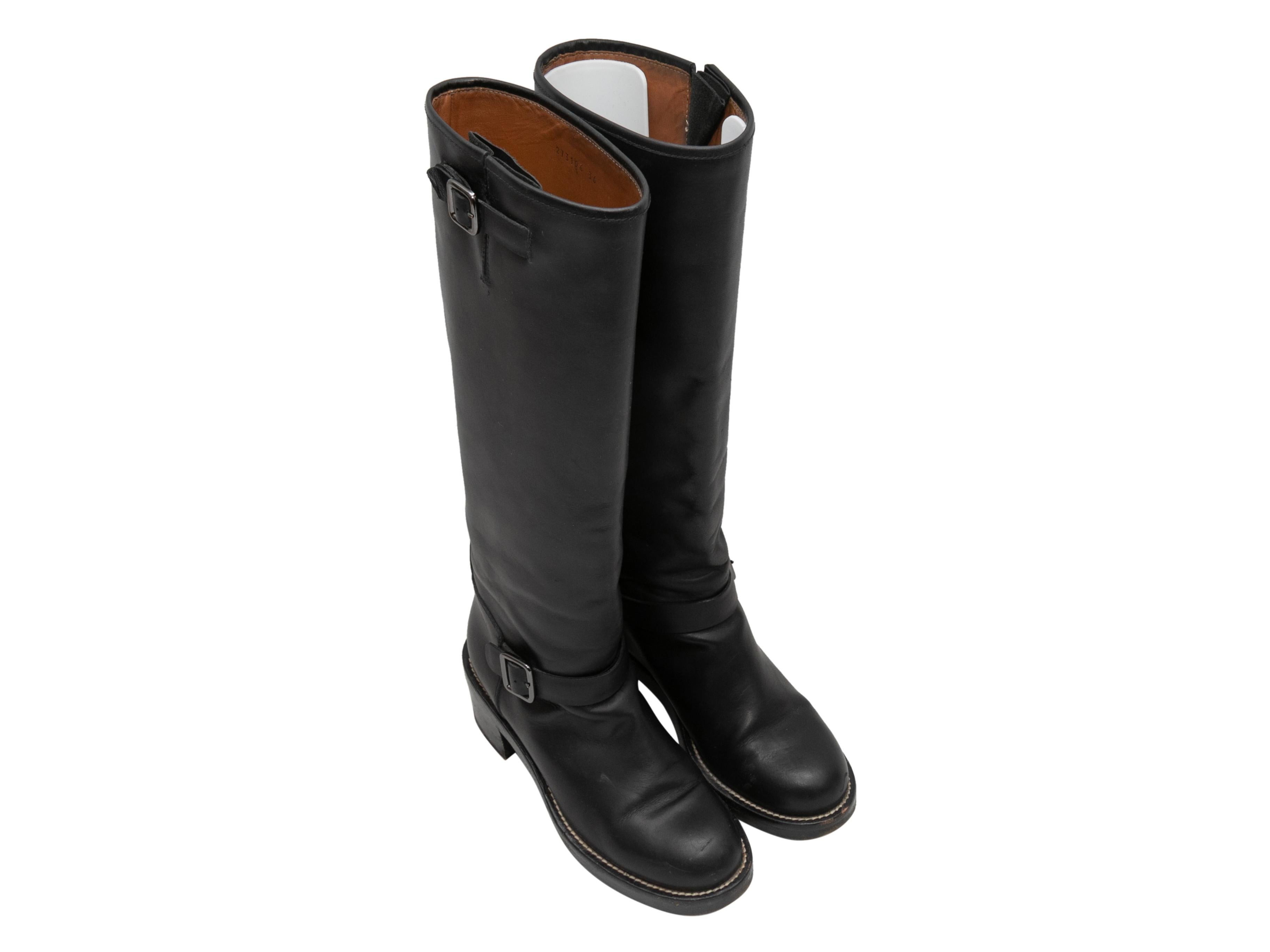 Black leather tall knee-high boots by Balenciaga. Buckle accents at sides. Stacked heels. 14.5