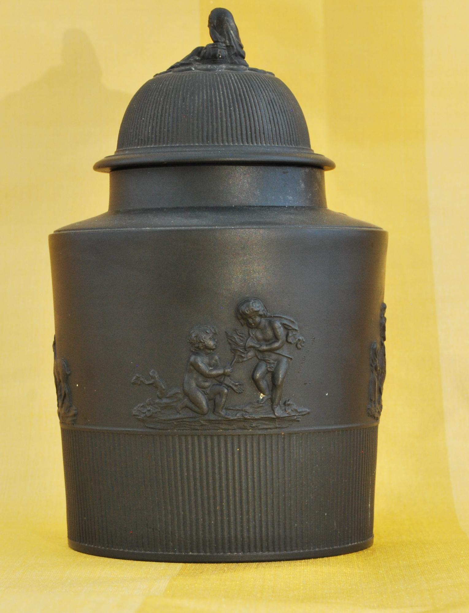 Cyclicrical tea canister in engine-turned black basalt, with raised decoration. Unmarked, but the quality and finial clinch the attribution.