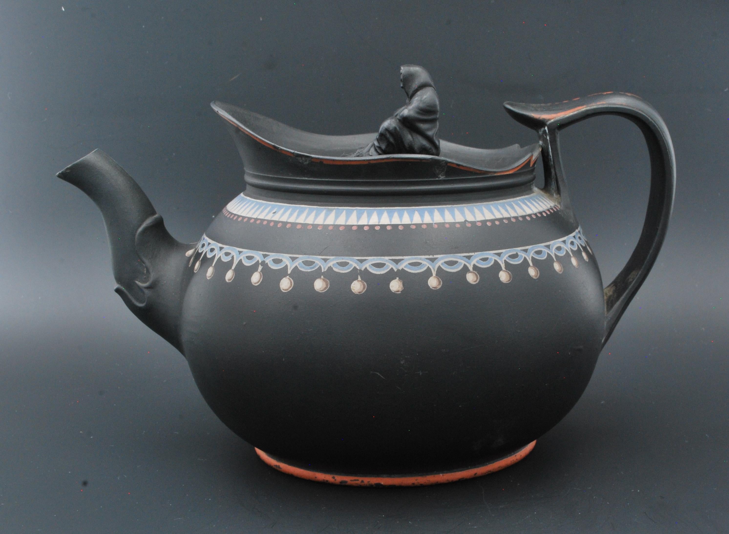 Globular teapot in black basalt, painted with matt white, red and ice blue. Judging by the shape and general appearance, probably by Spode, in imitation of Wedgwood designs of the period.