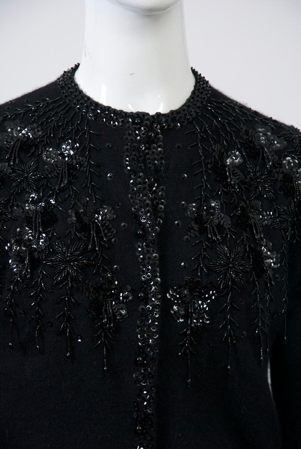 Black cardigan from the 1950s-'60s embellished with black beads and sequins. Sweater composition is lambswool, angora and nylon and has tiny spherical buttons. Lined. Retailed by Gimbels department store, which was located on 34th St. in NYC.