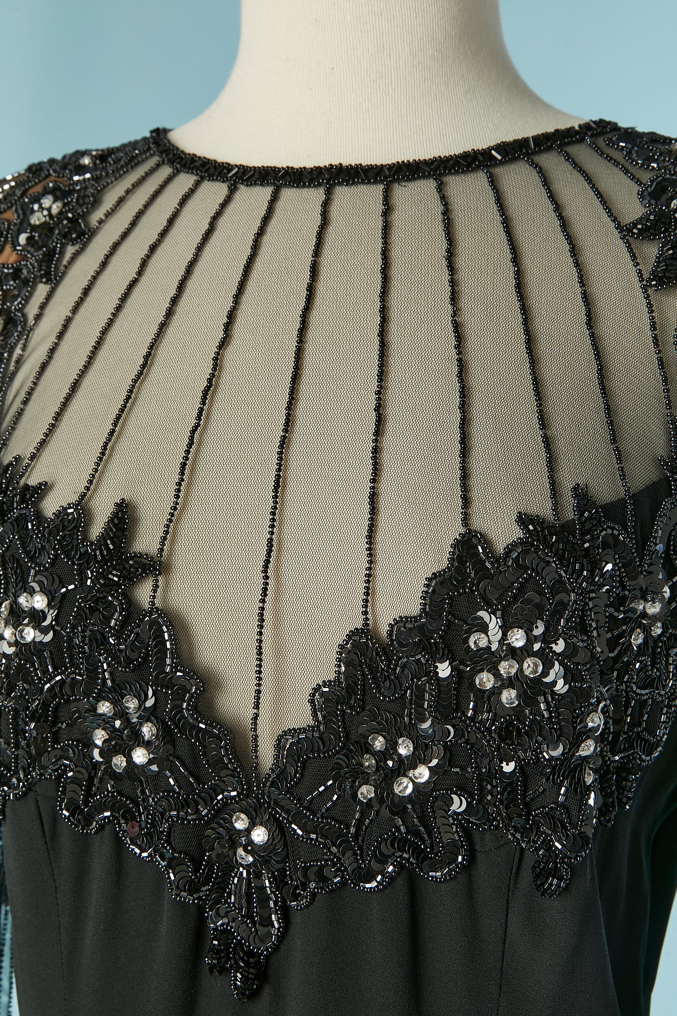Abito da cocktail nero con perline (paillettes, perline e strass). Composizione del tessuto principale: 100% rayon. Fodera: 100% nylon. La parte superiore dell'abito è in tulle trasparente. 
Spallaccio. Zip e gancio sulla parte centrale della