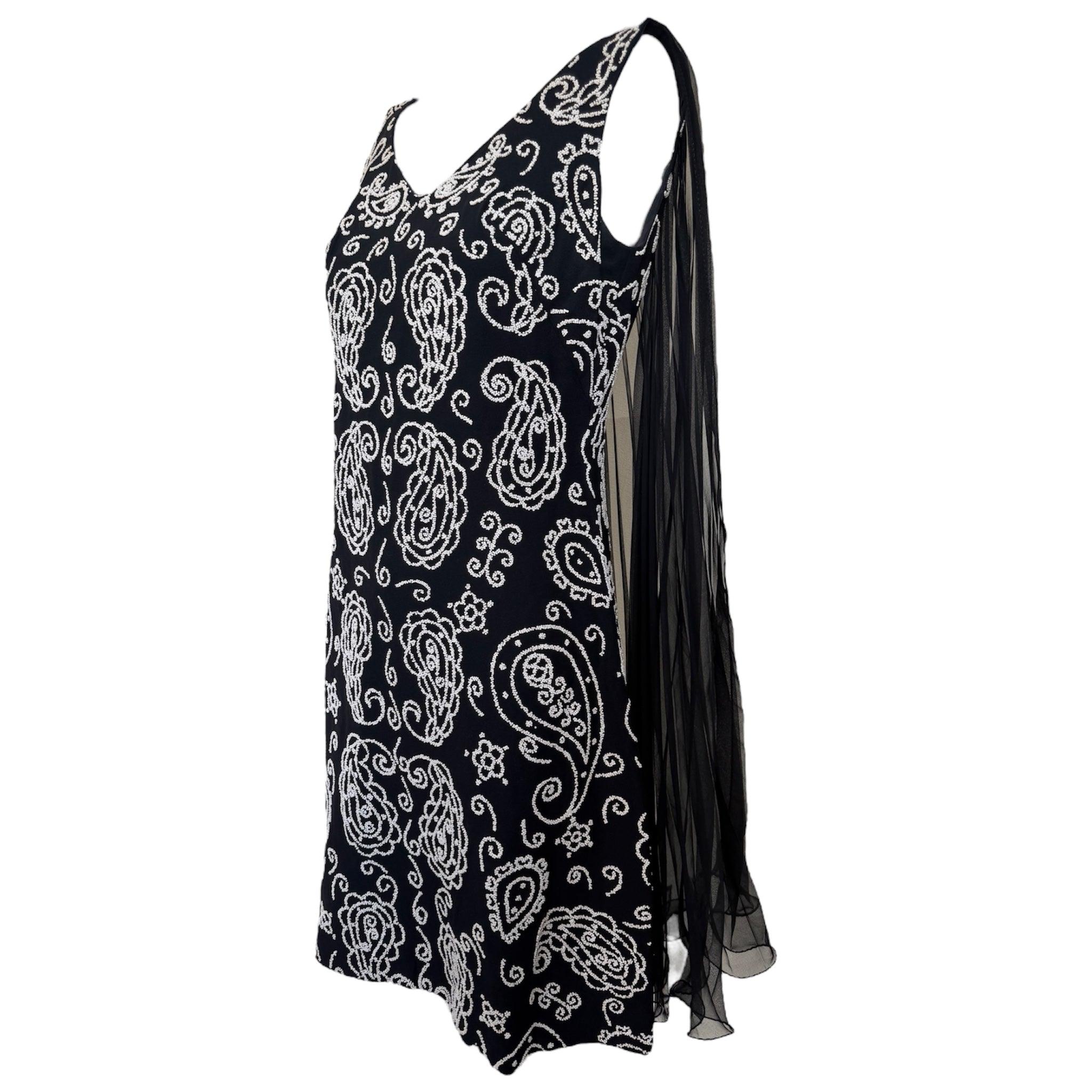 Mini abito degli anni '60, adorabile e pieno di perline. Un pannello svolazzante in chiffon nero a pieghe scende lungo la schiena. Leggero scollo a V sul davanti, profondo scollo a V sul retro. Le perline bianche sono presenti sulla superficie e