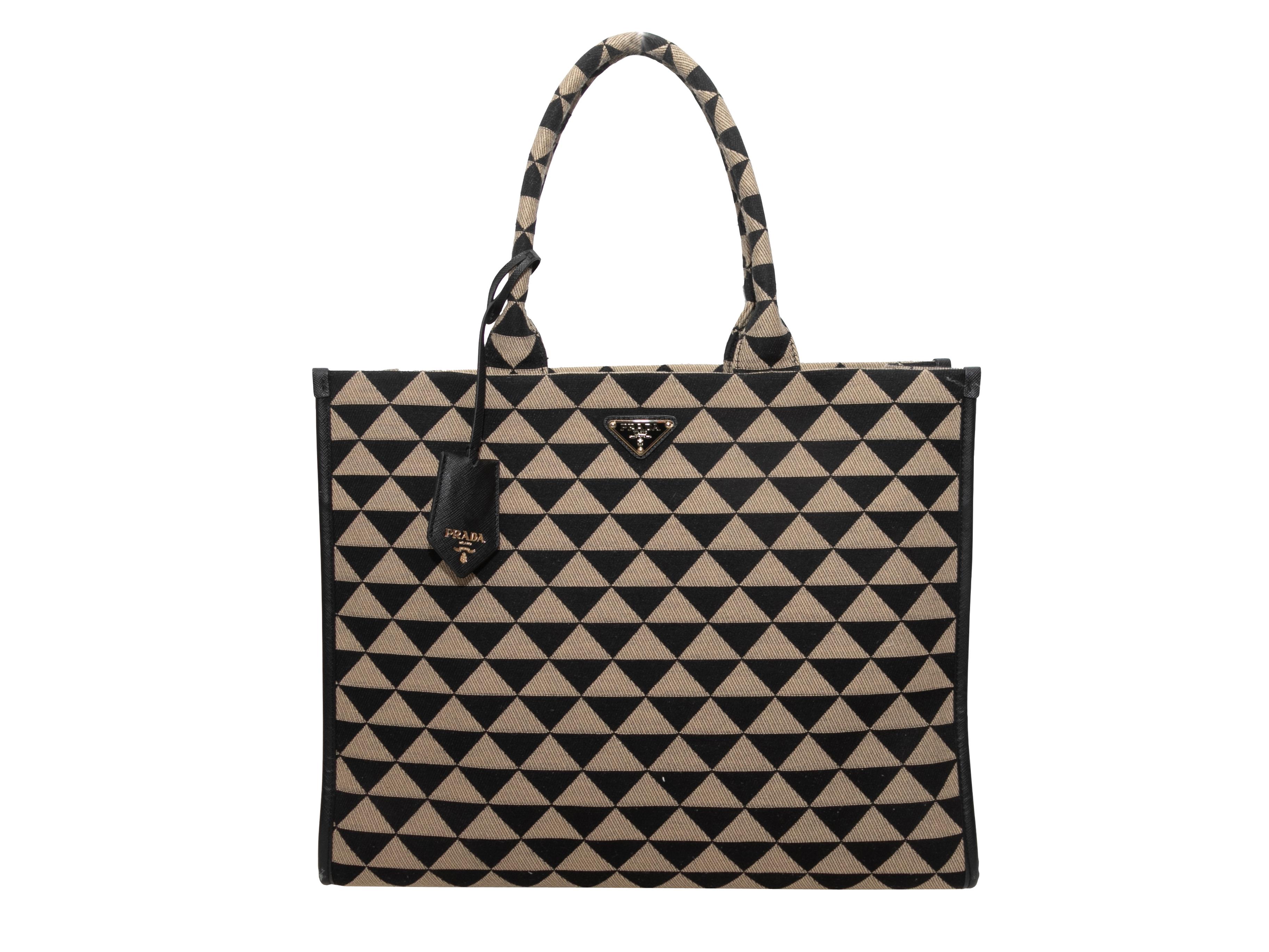 Product Details: Black & Beige Prada Large Symbole Embroidered Tote Bag. The Large Symbole Bag features an embroidered triangle patterned body, leather trim, gold-tone hardware, and dual rolled top handles. 15.25