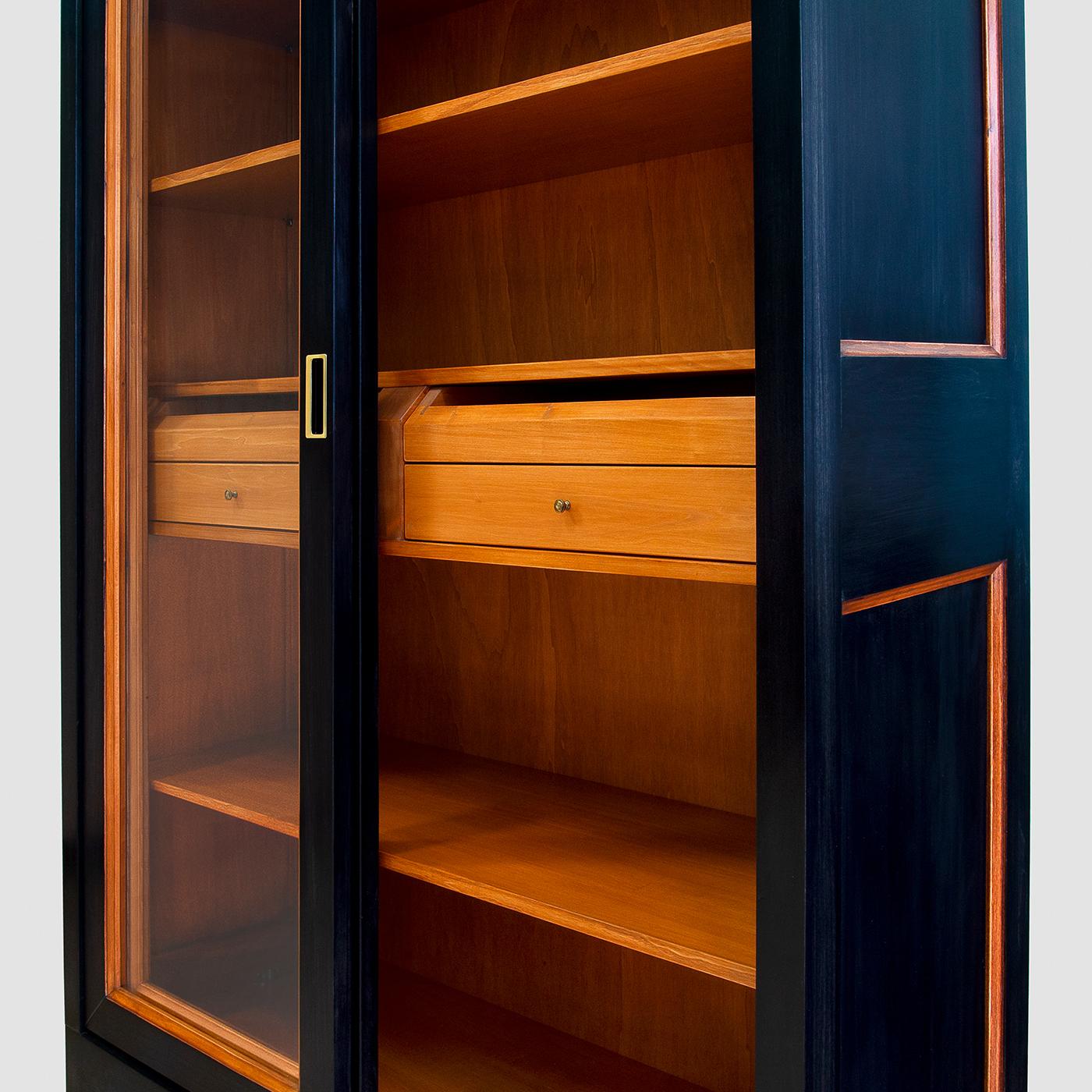 This luxe bookcase exemplifies Italian cabinetry tradition. The solid lime frame features two sliding glass doors and side glass panels that allow for an unobstructed view of some of the books and objects displayed on the three wooden shelves and