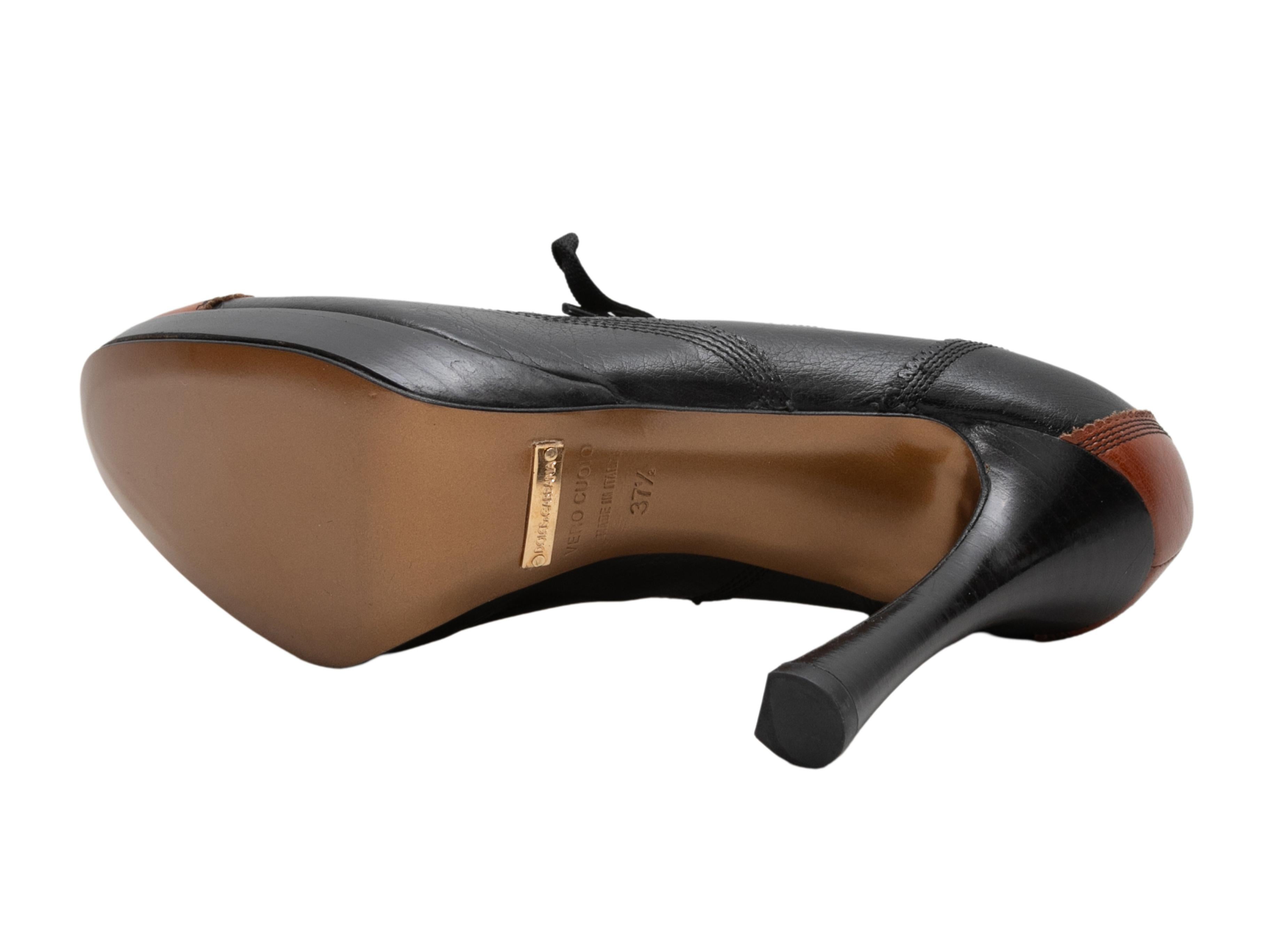 Black and brown cap-toe leather oxford pumps by Dolce & Gabbana. Stacked heels. Lace-up tie closures at tops. 1